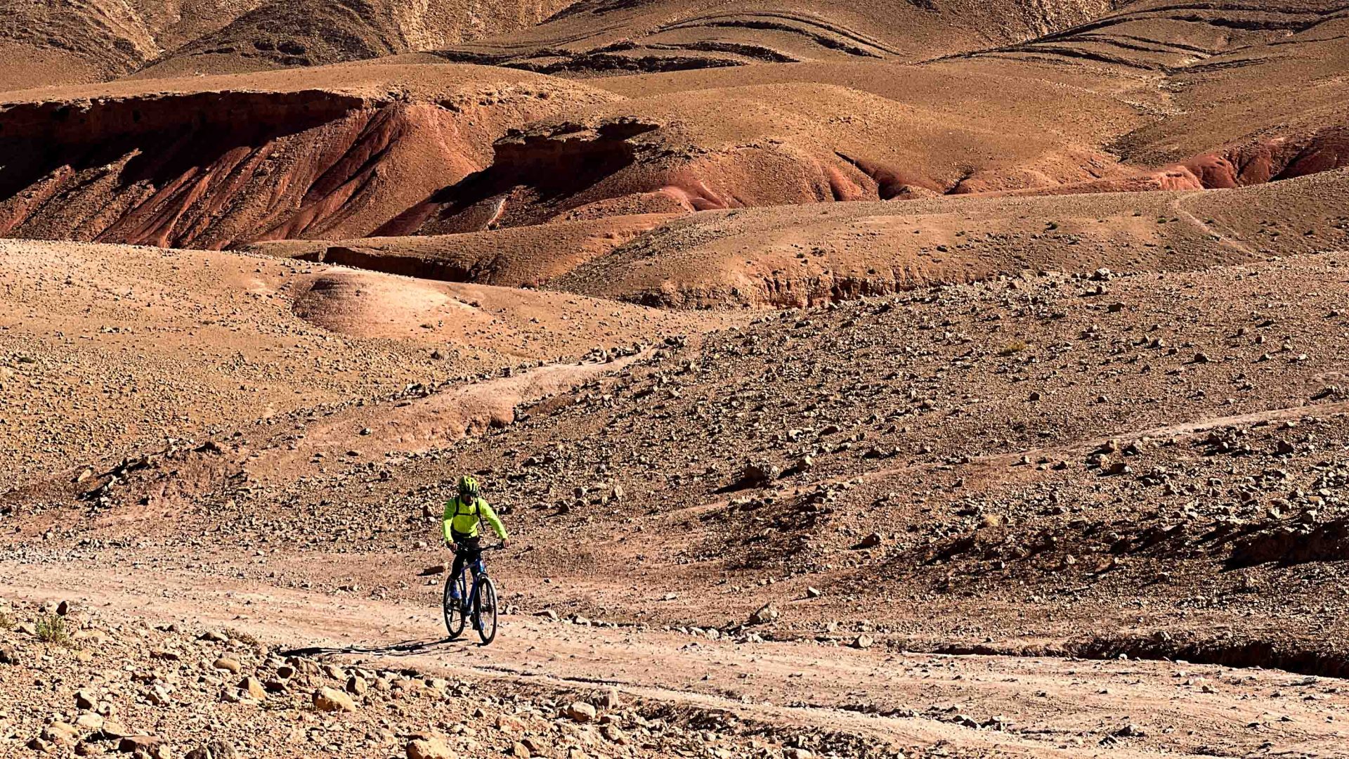 A cyclist traversing a dry, rocky landscape.