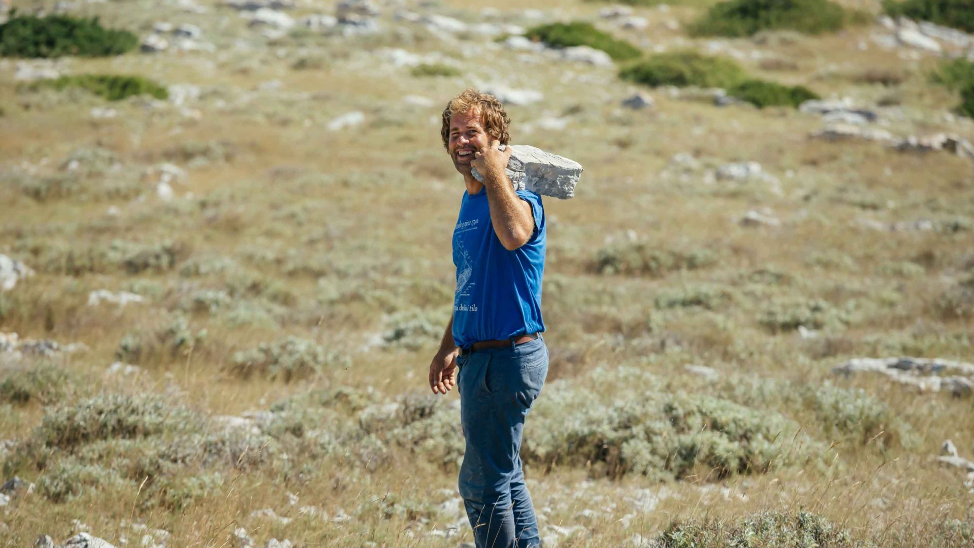 Jakov holds a large stone on his shoulder.