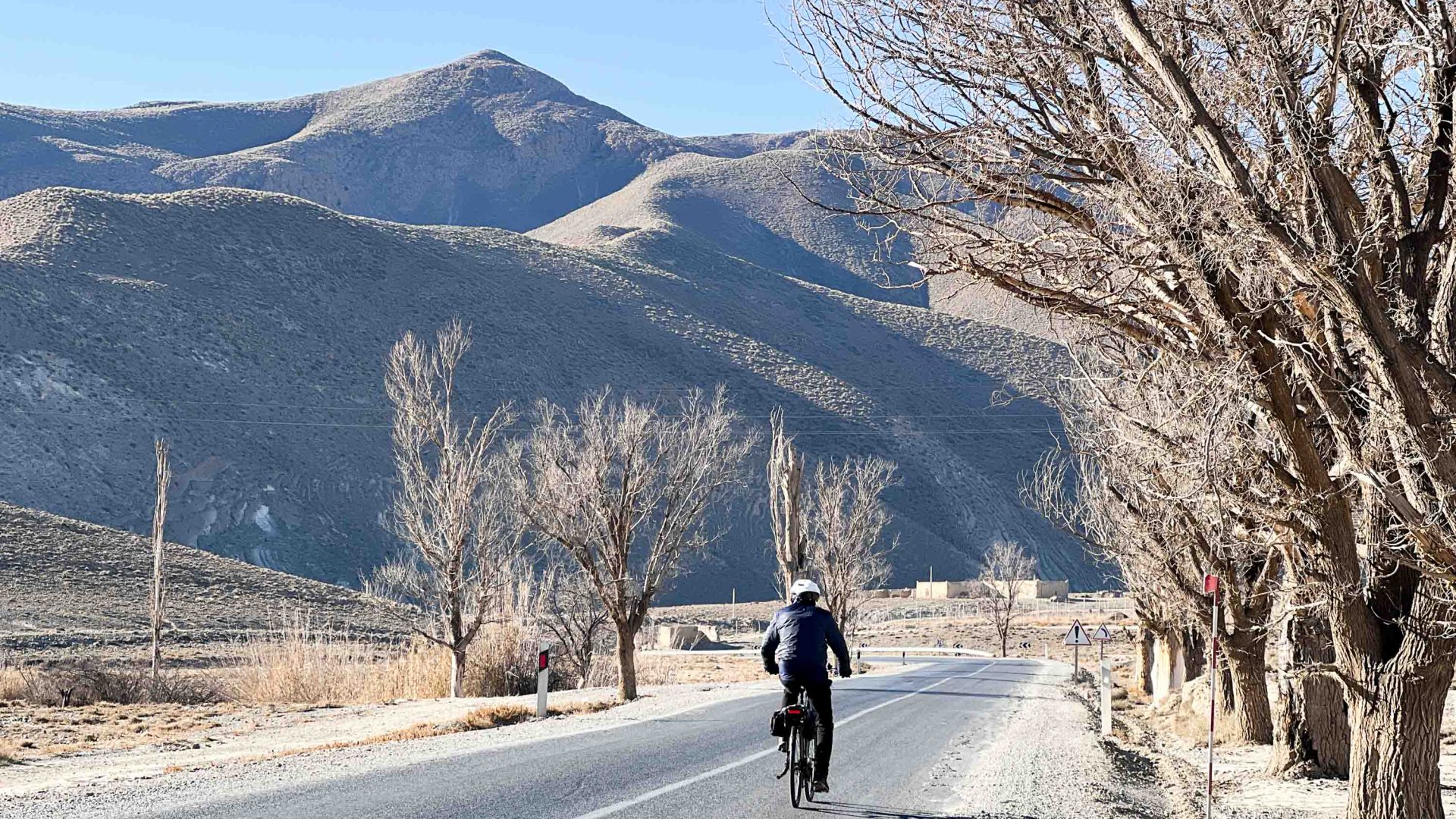 A cyclist along a mountain road in winter.