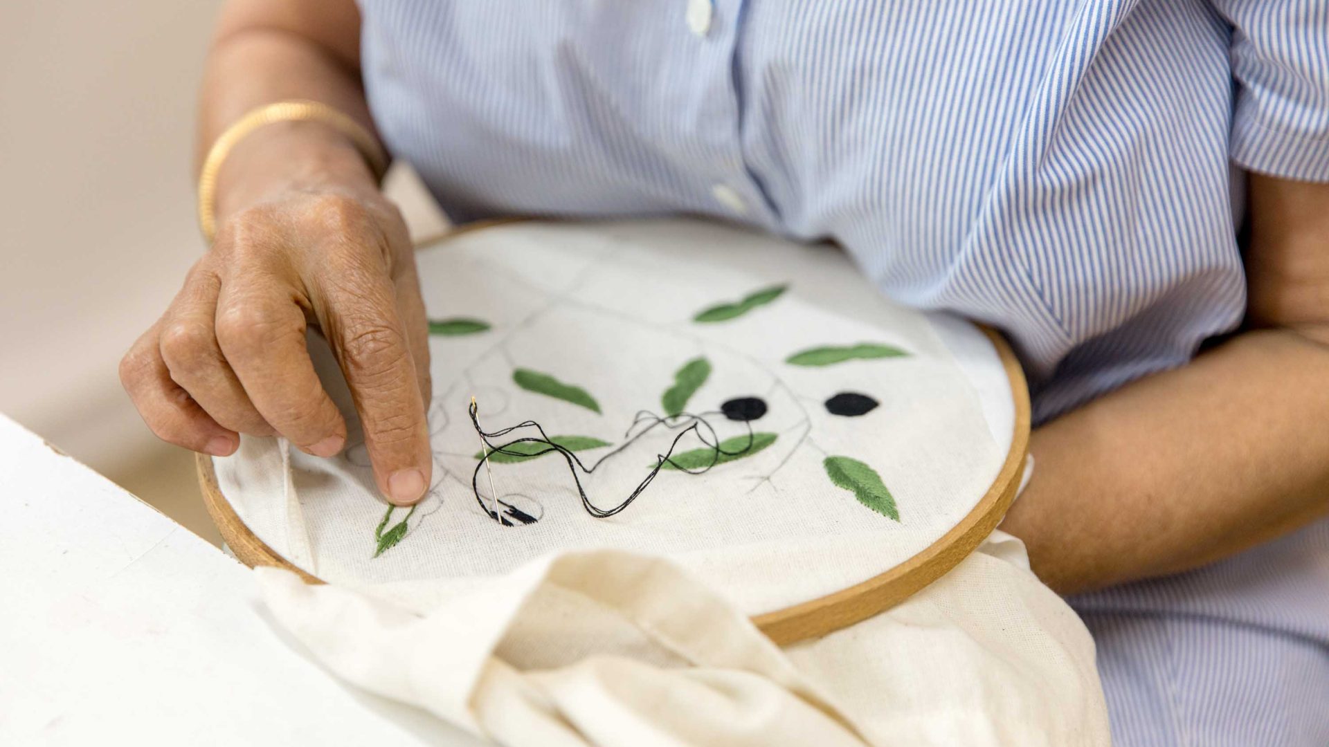 A close up of an older woman's hands embroidering.