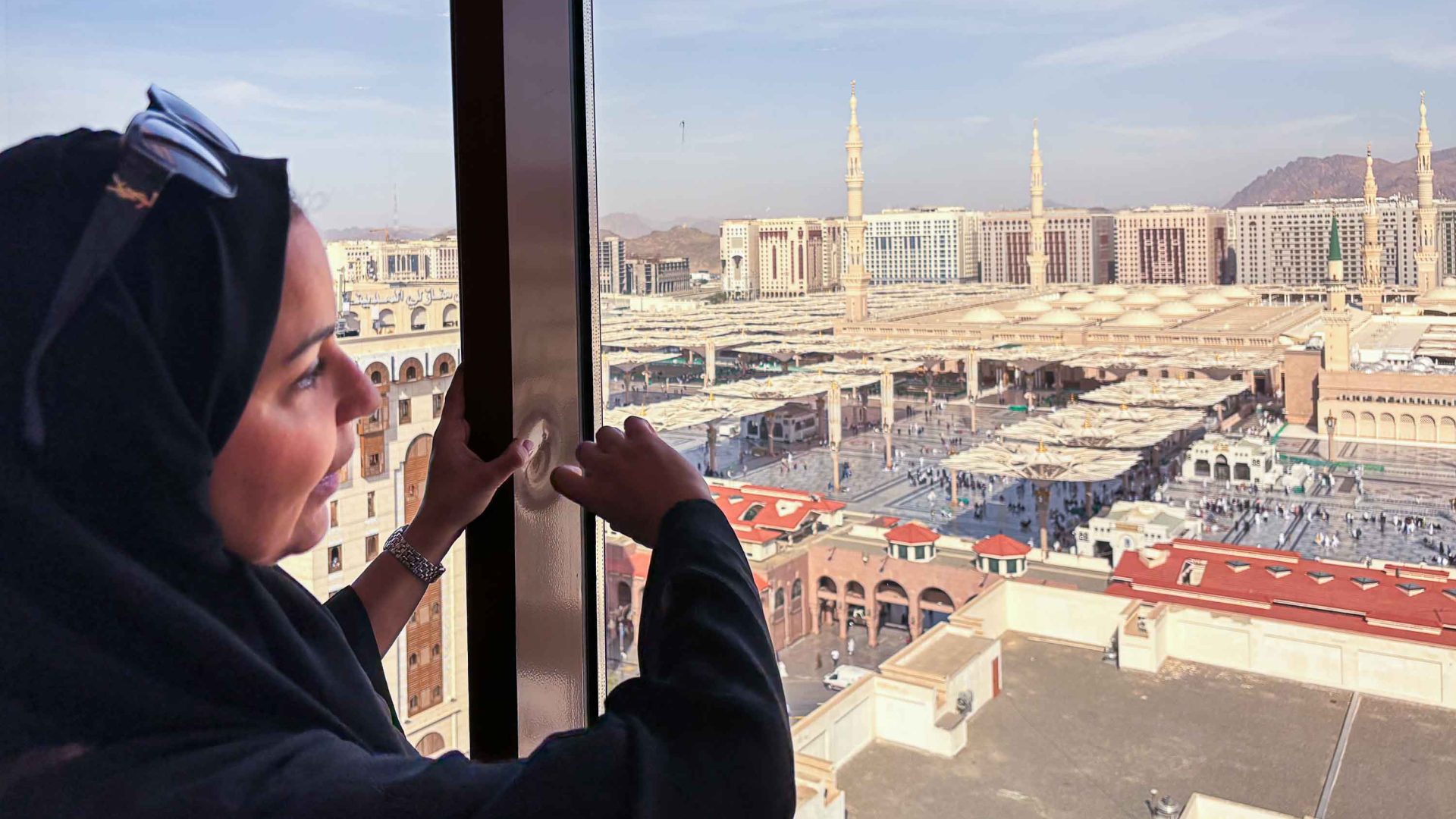 A woman in a hijab looks out over a mosque.