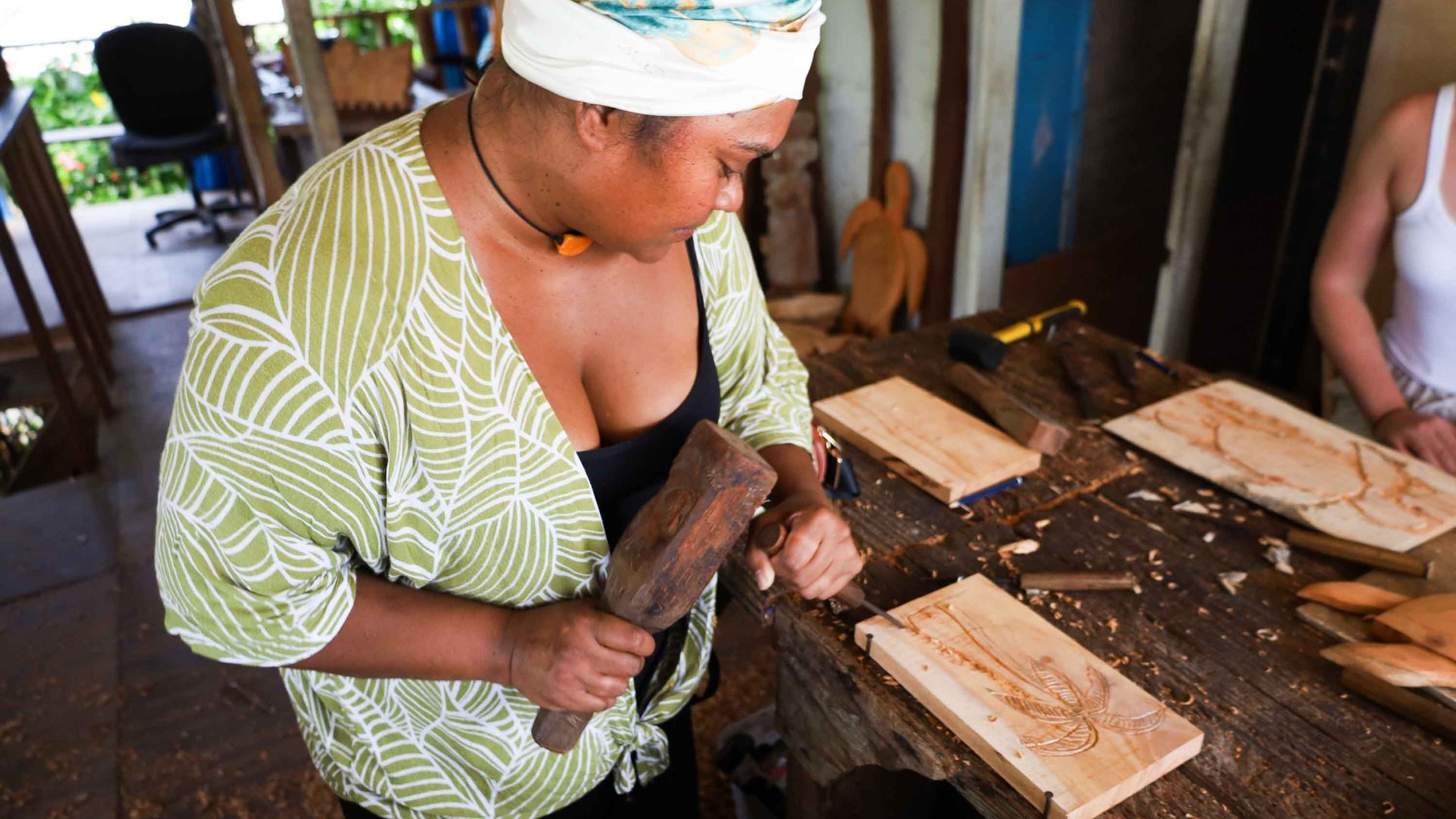 A woman works on a wood carving.