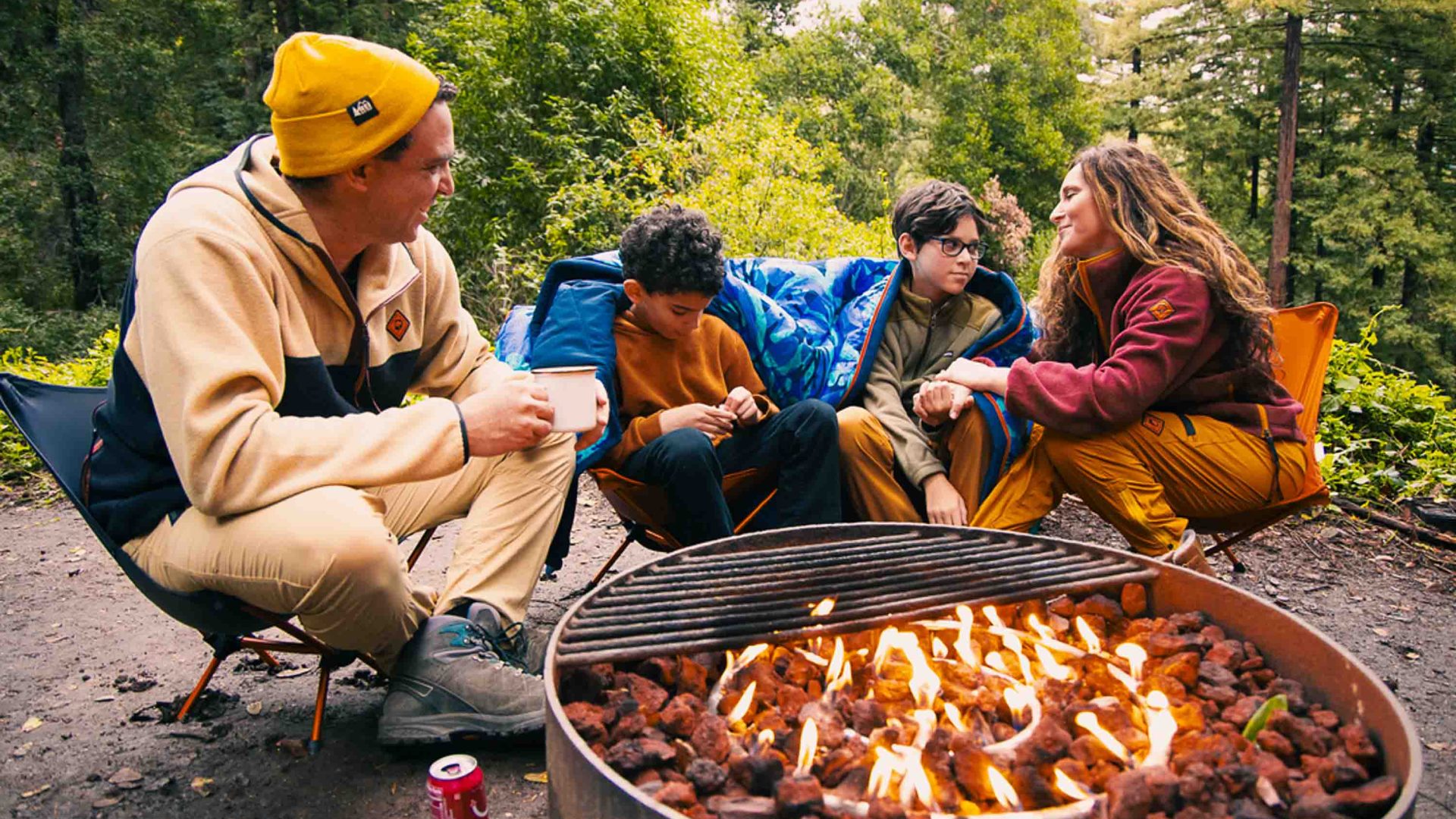 People sit around a fire wearing REI apparel.