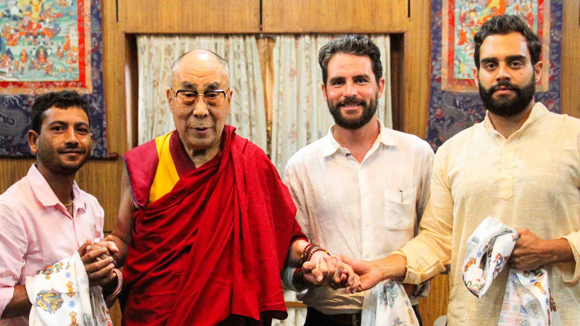 Ash stands with the Dalai Lama and some other people.