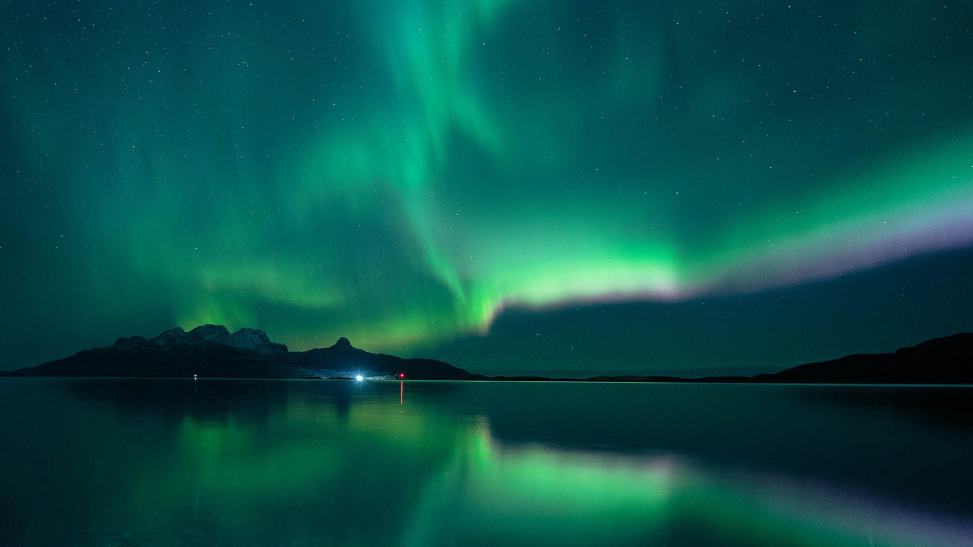 An example of the aurora borealis with a green sky over a still lake.