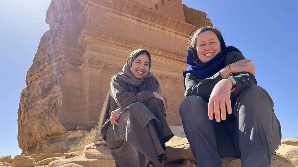 Two women in front of an archaeological site in the desert