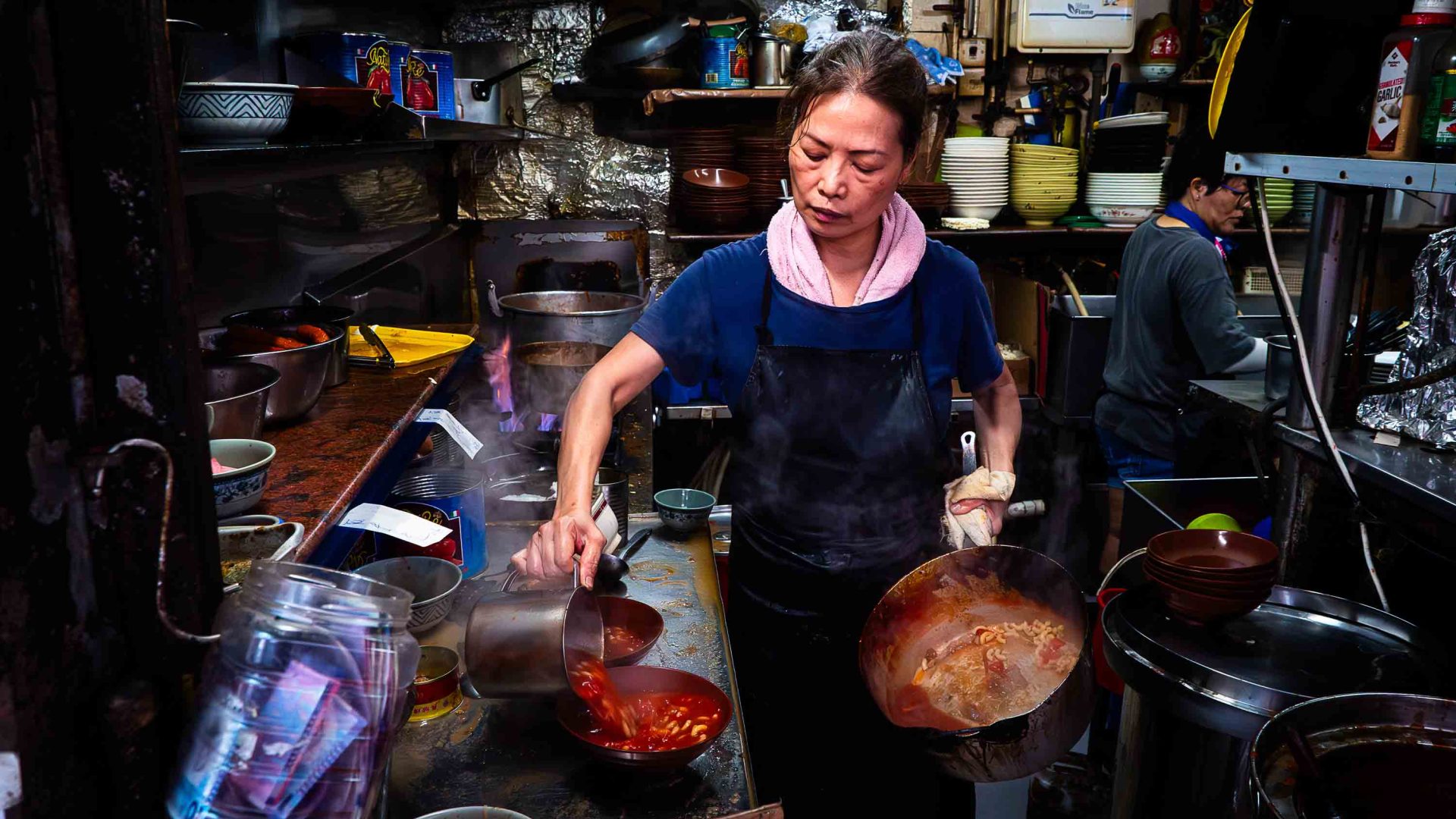 A female chef cooks tomato soup in a kitchen.