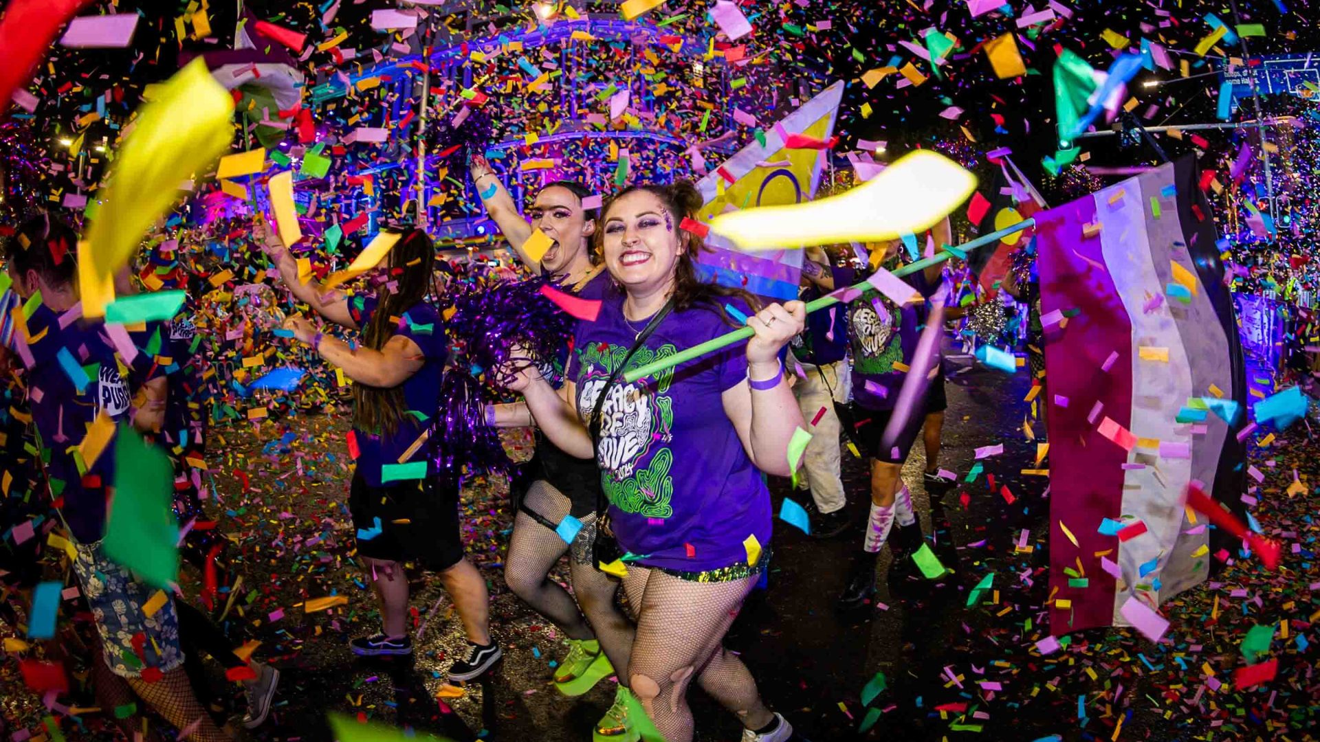 A group marches in the Sydney Mardi Gras, surrounded by confetti.