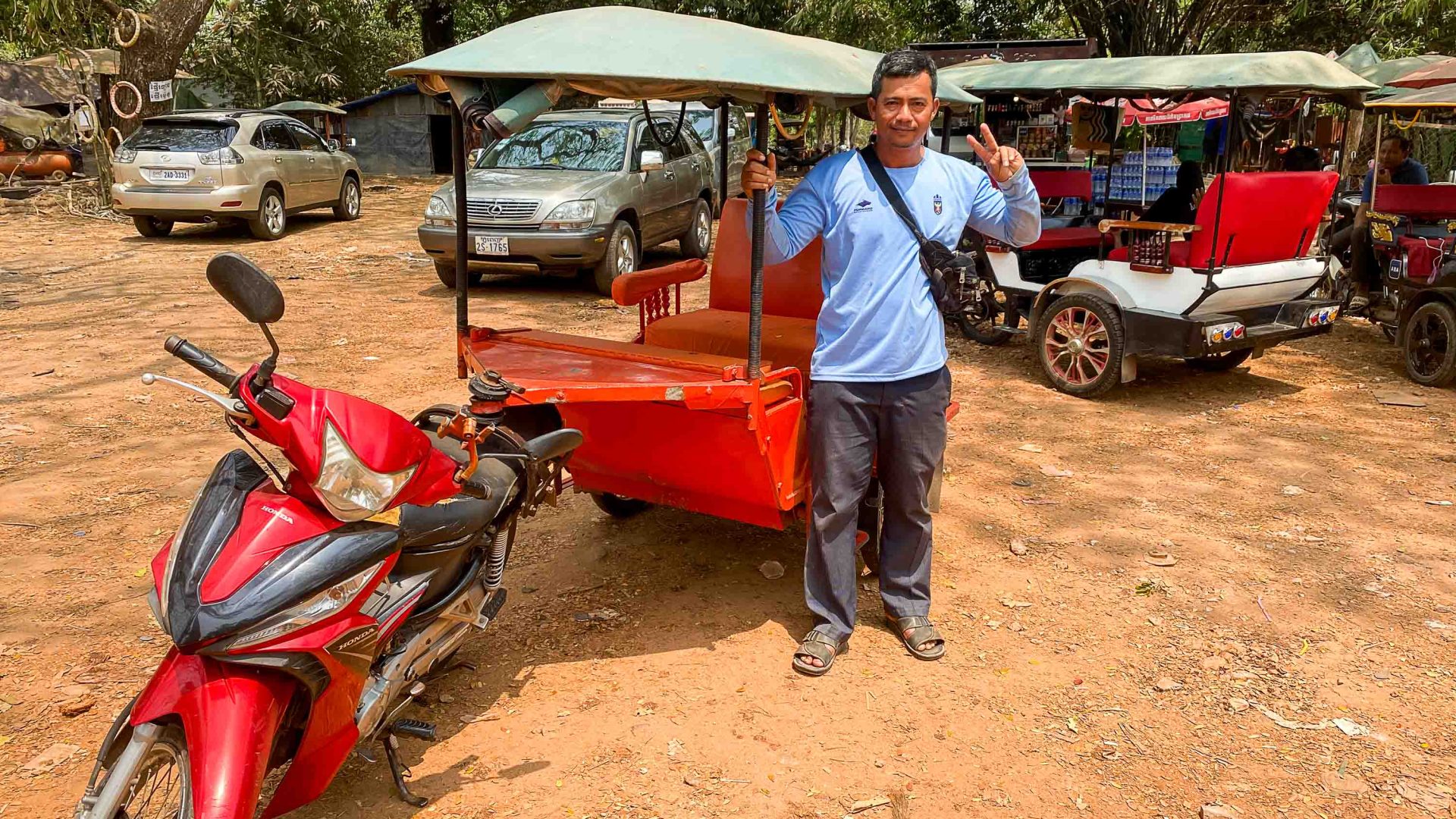 Sam Savat with his tuk tuk and other tuk tuks in the background.