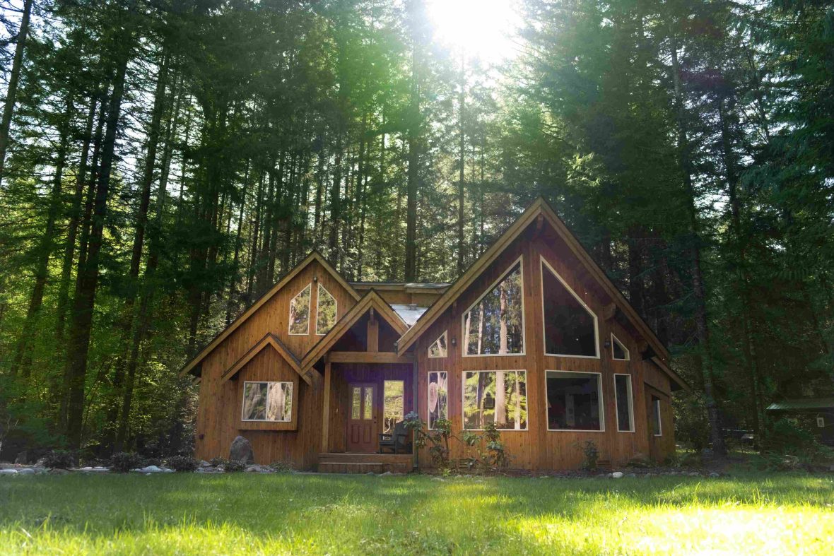 A luxury wooden chalet lodge in the forest with the sun shining through the trees