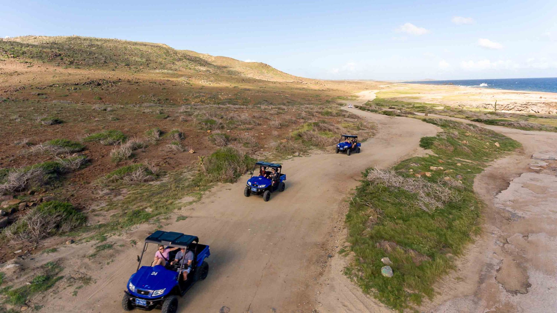 Tourists enjoy an ATV tour through sparse scrub.