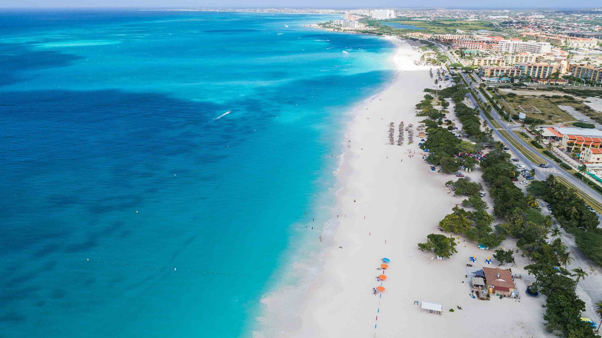 Hotels line the white sand of a beach.