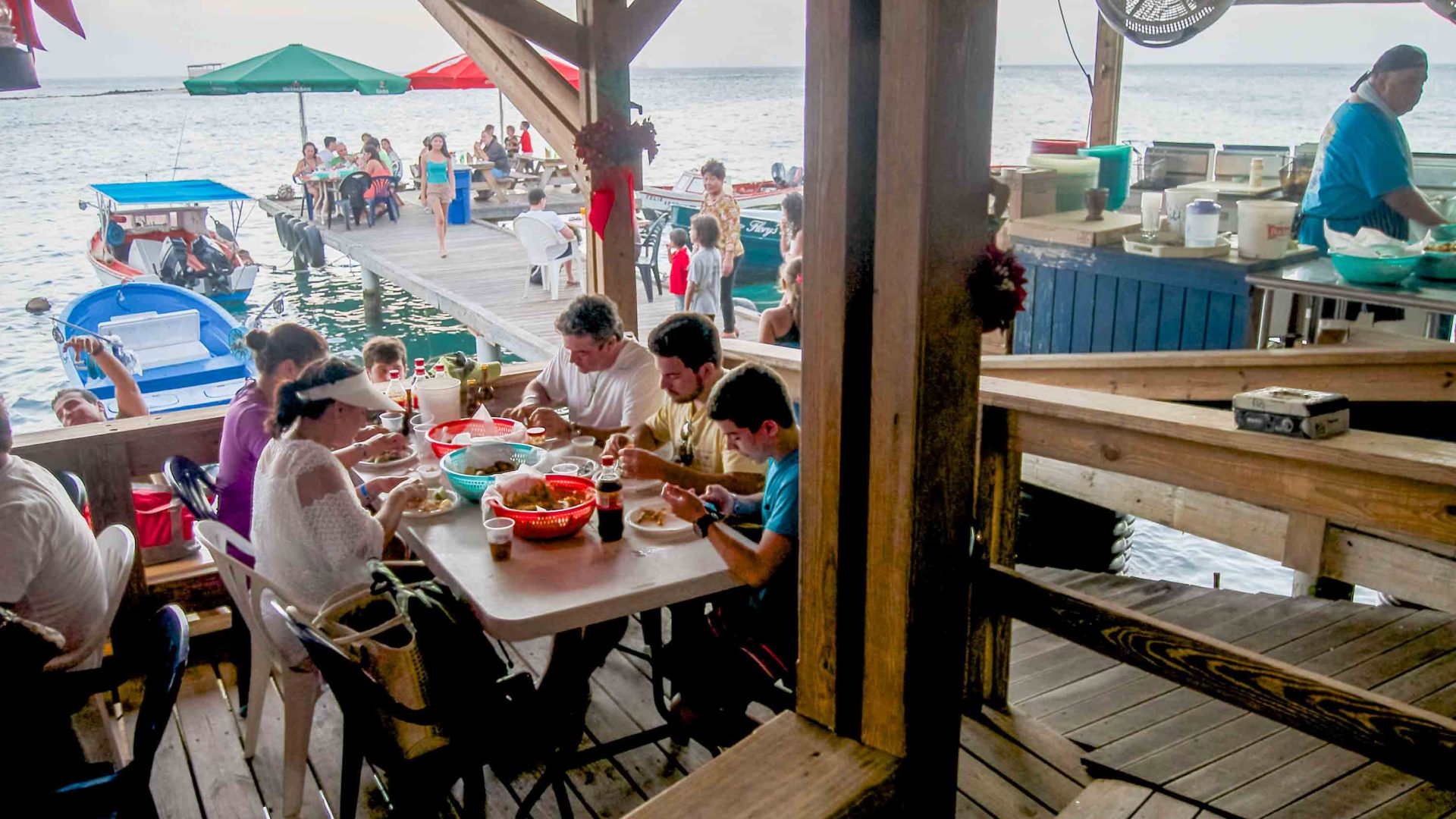 Tourists dine at a restaurant on the water with plastic plates.