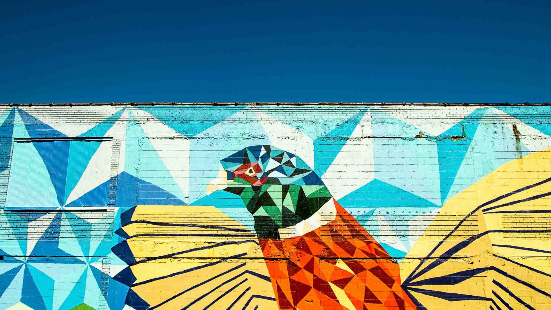 A street art mural of a bird in bright colors.