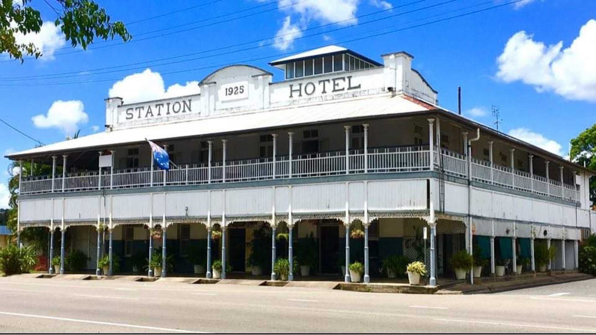 A two storey white hotel with the words 'Station Hotel' painted on it.