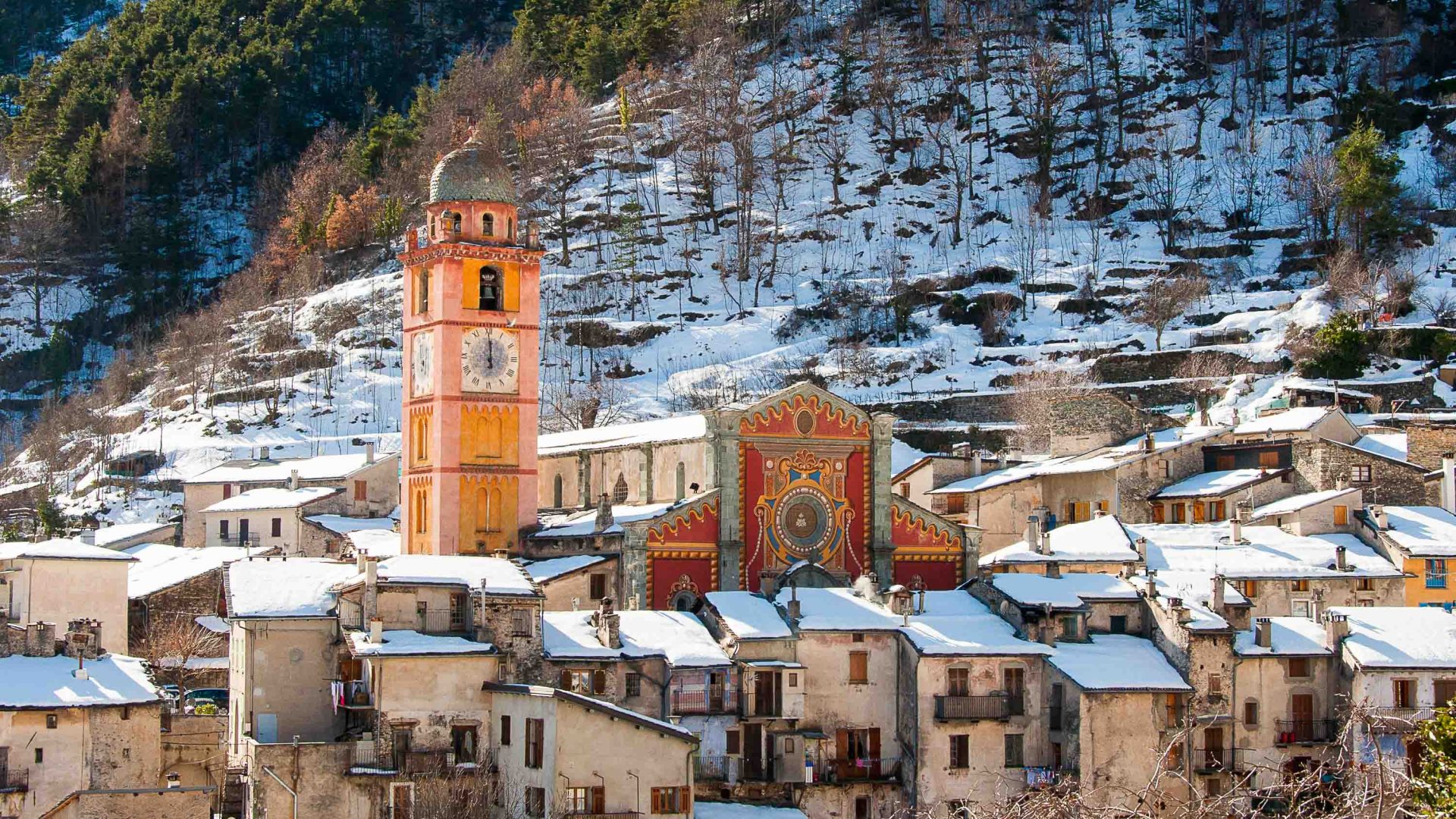 The town of Tende with snow on the ground. A peach coloured church dominates the pictire.