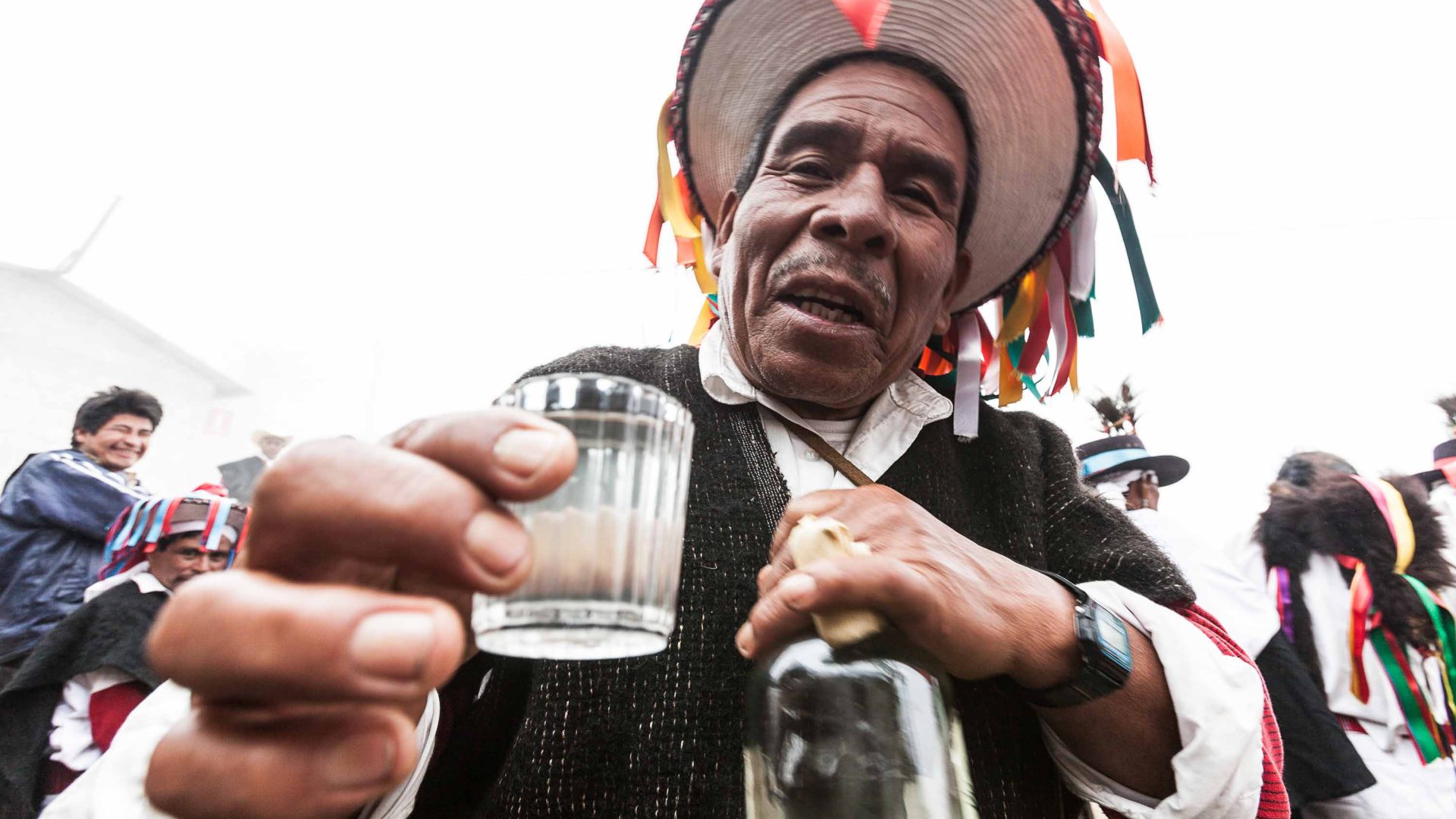 An Indigenous man holds up a glass of pox.