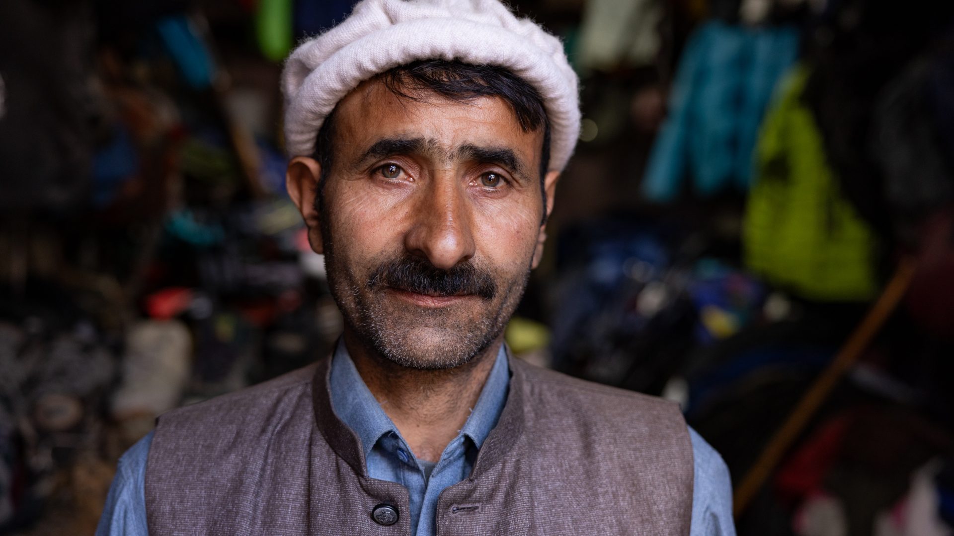 A man in a traditional cap smiles to the camera.