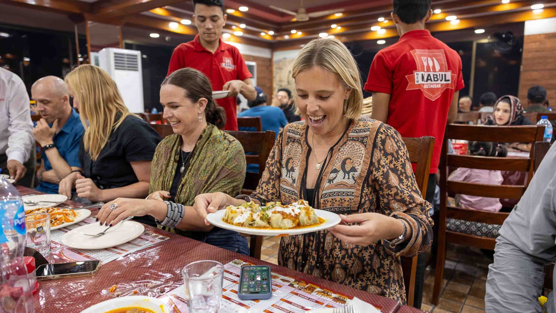 The writer Sarah enjoys some Afghan dumplings. She is at a table with others from the tour.