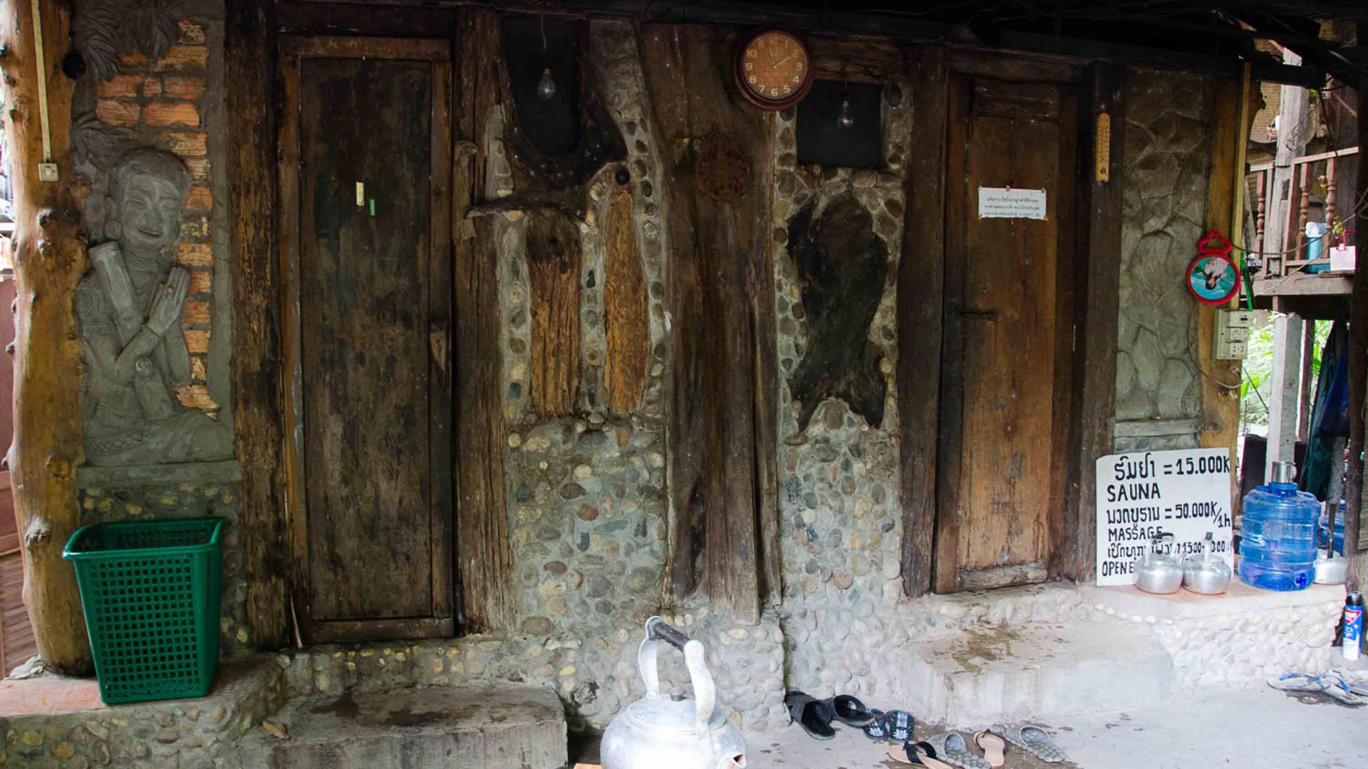 A sauna in Laos with wooden doors, and robes hanging up.