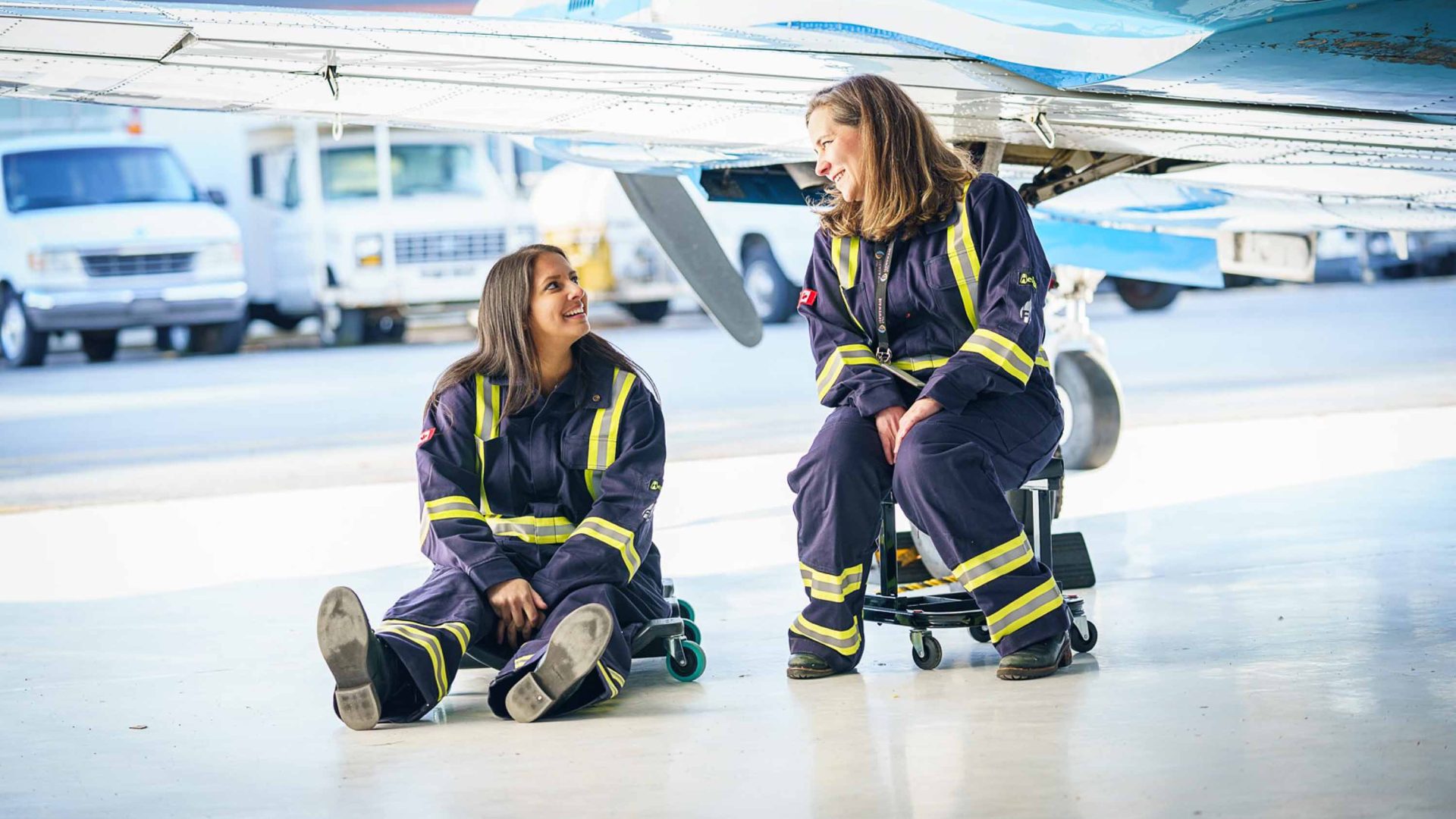 Teara and a staff member sit in the airplane hangar.