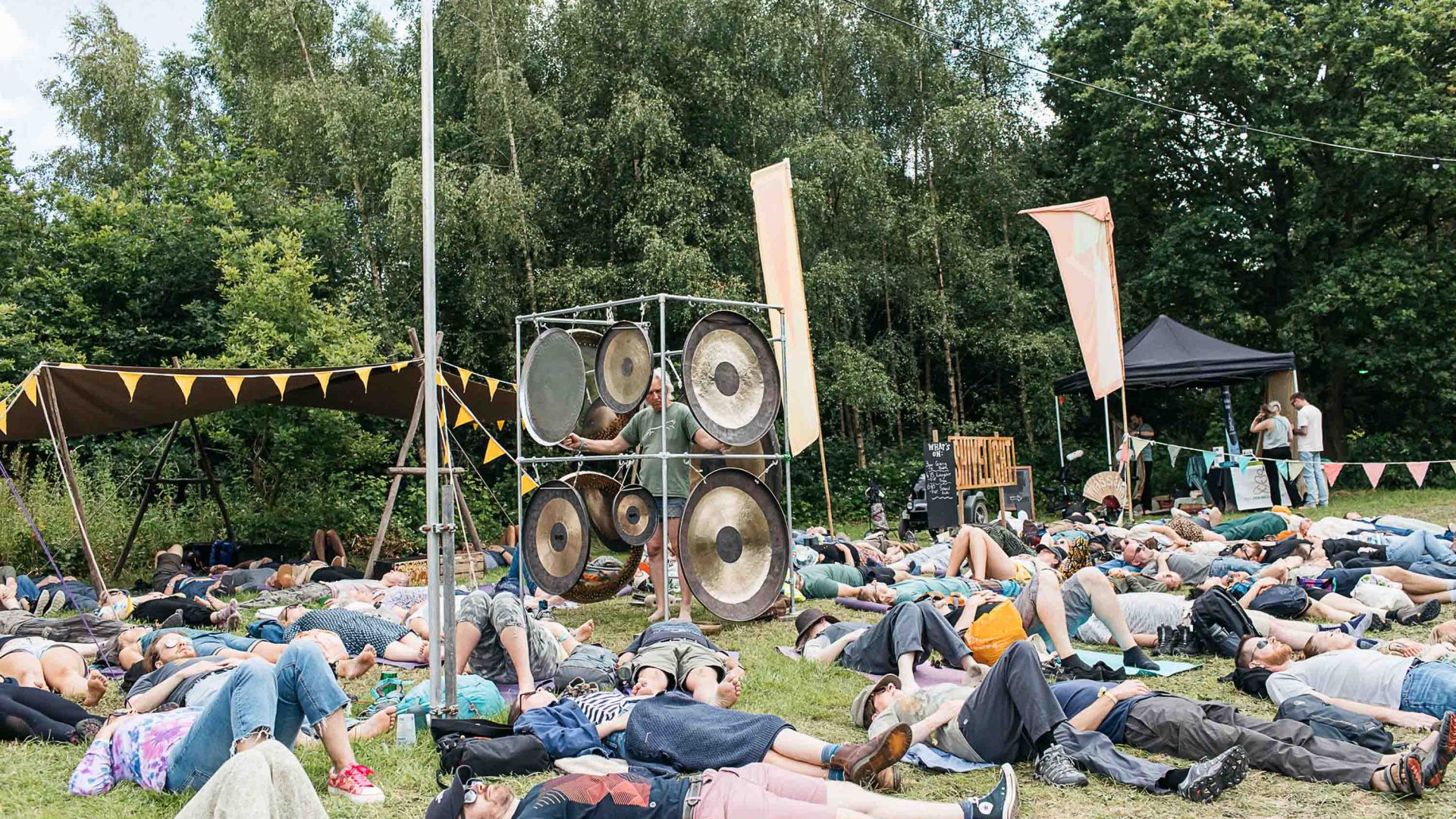 Festivalgoers lie on the ground listening to something calming on the speaker.