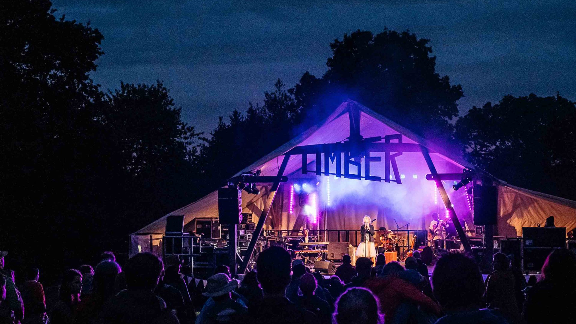 One of the festival stages at night, lit up by purple lights.