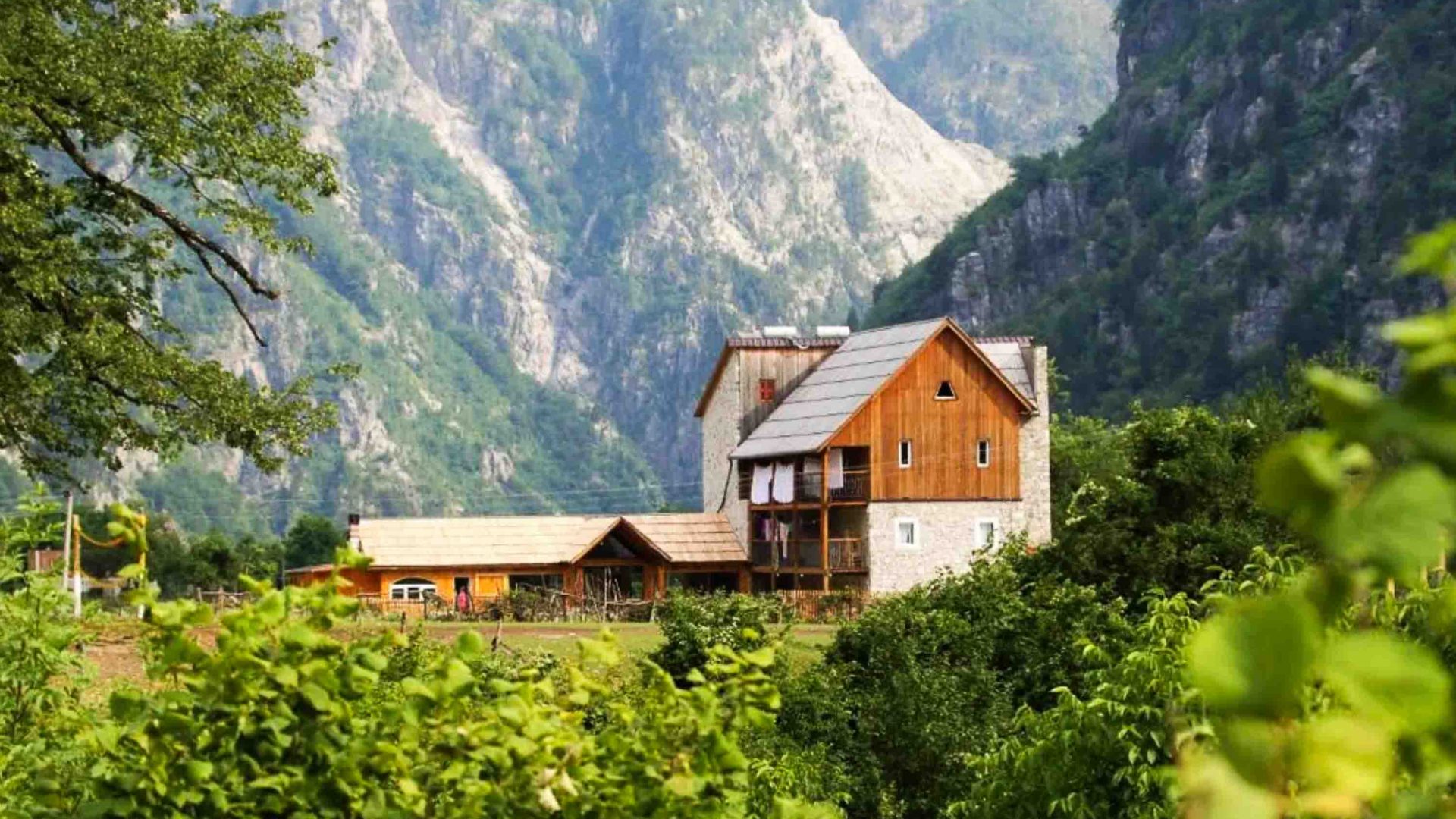 A guesthouse in a field backed with mountains.