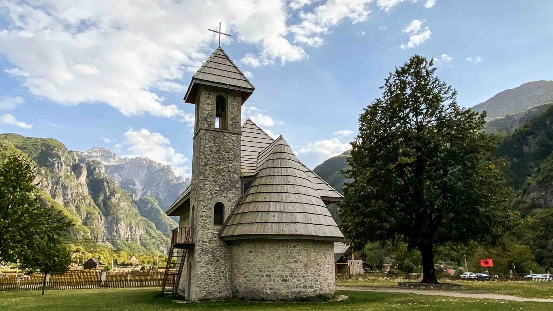 A stone building nestled in the trees and hills.