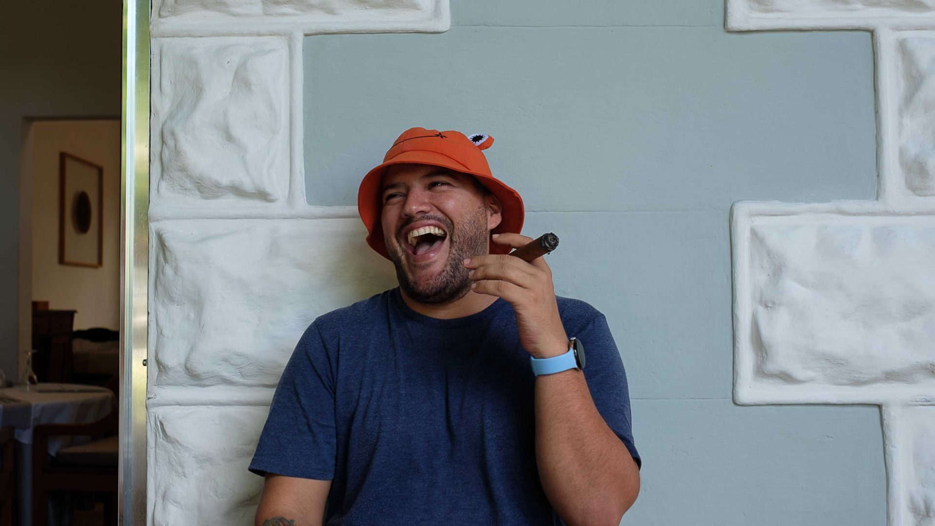 A man laughs while smoking a cigar.