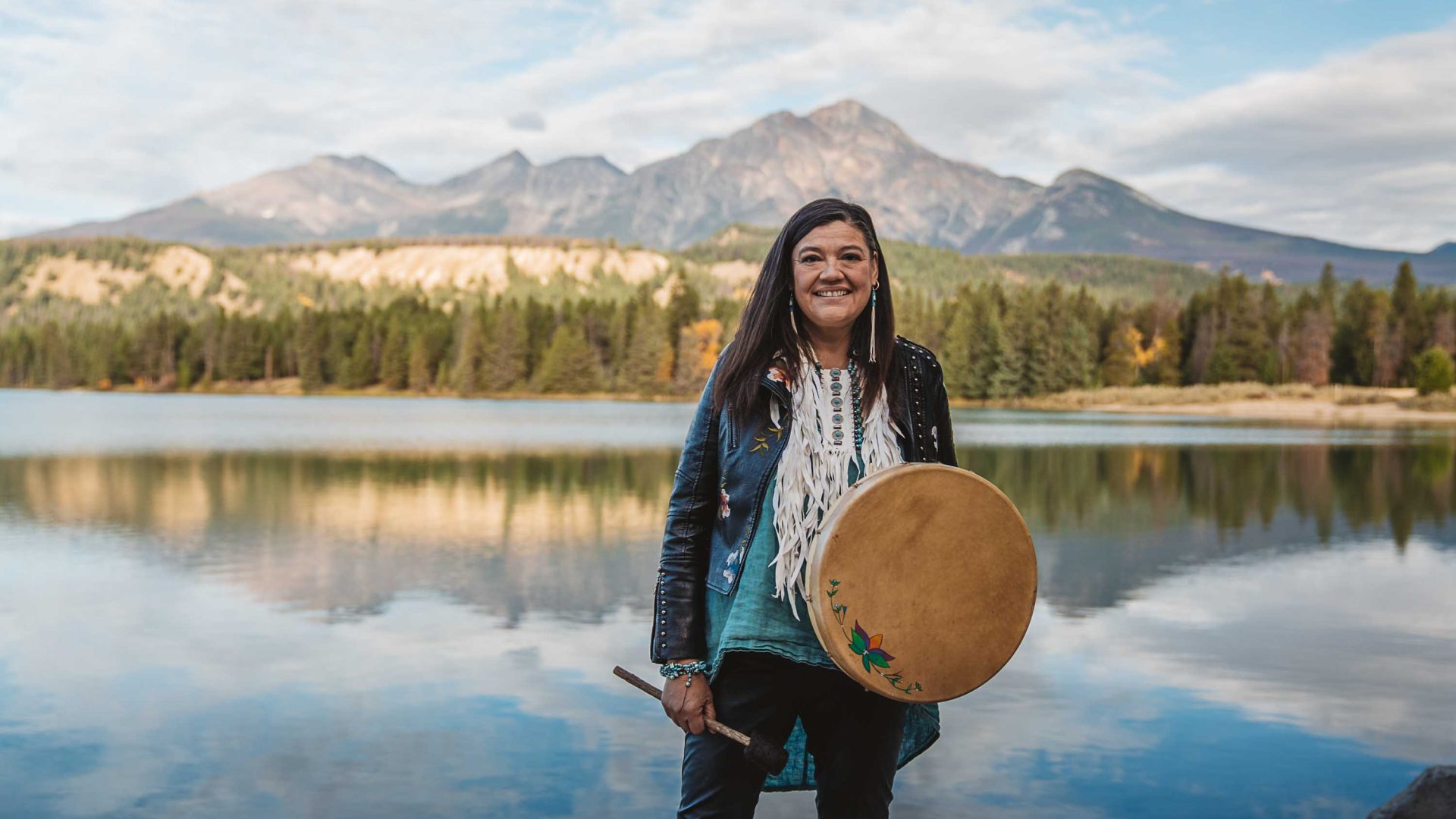 A woman stands in front of a lake.