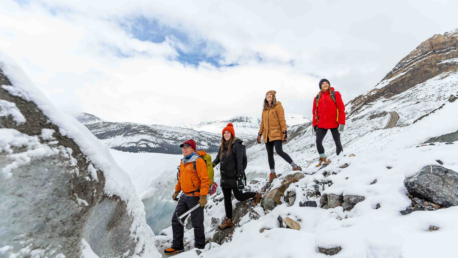 A man guides three others across a glacier.