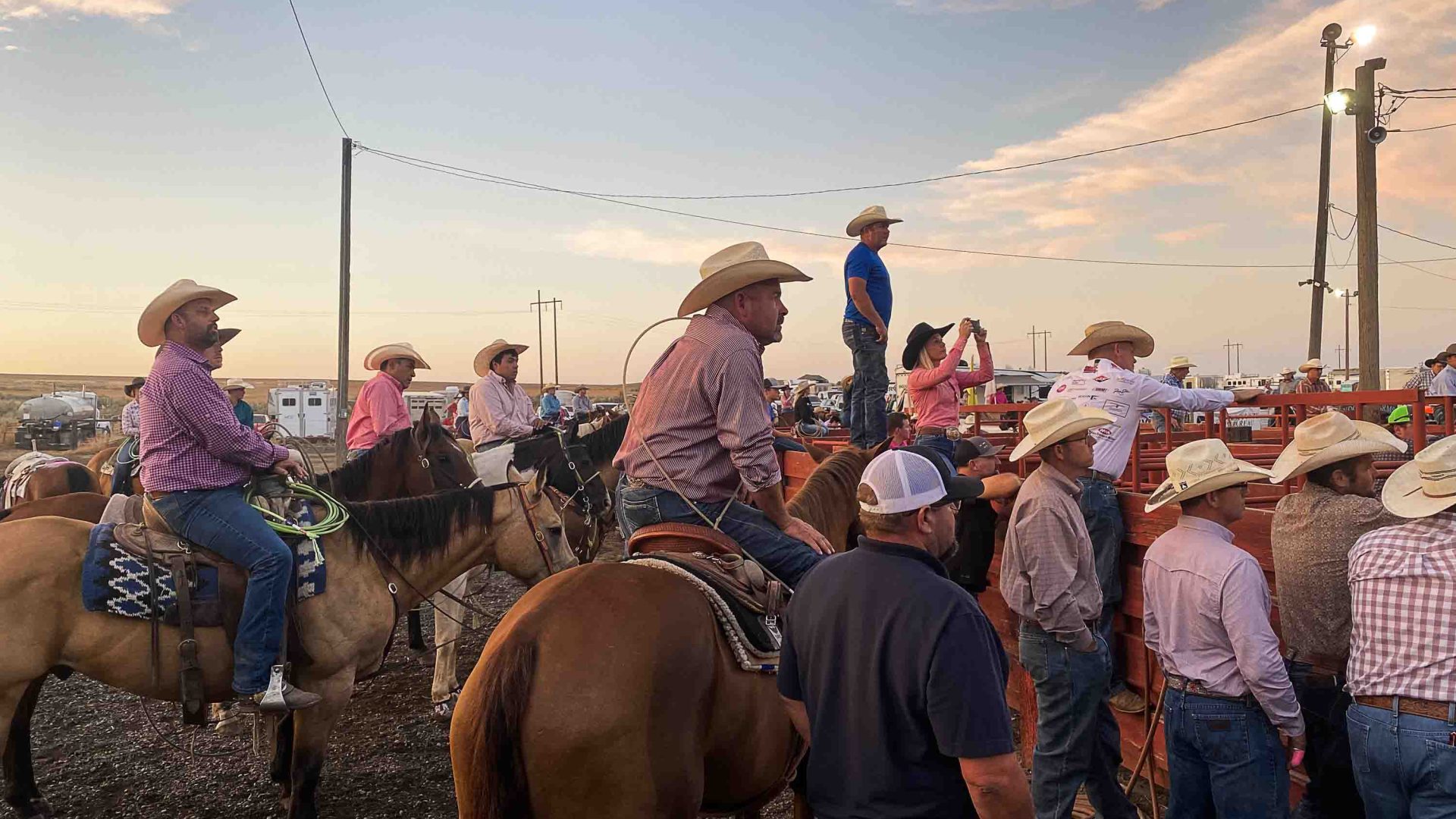 People in cowboy hats watch a rodeo.