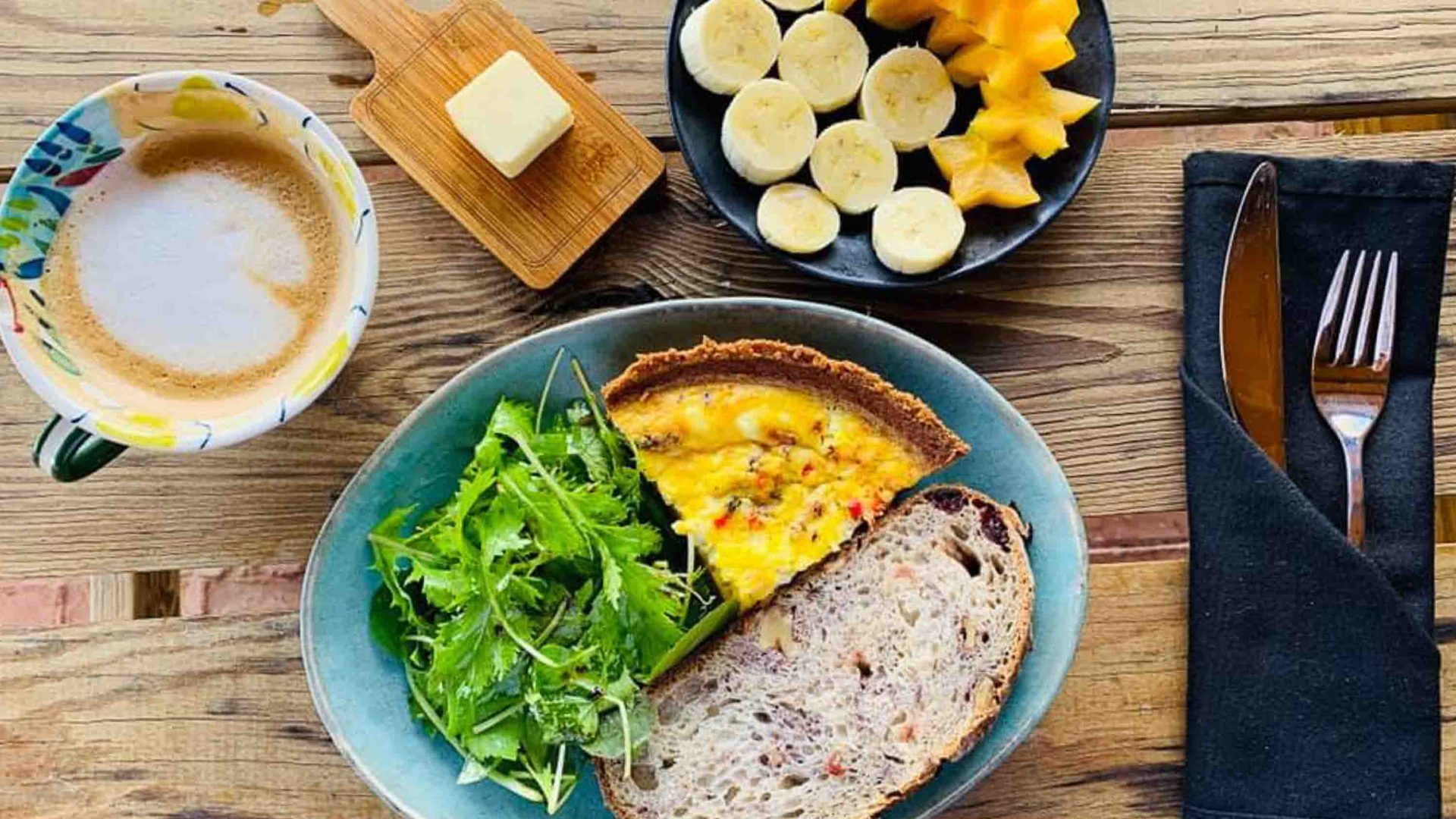 A plate of bread, salad and quiche, alongside a plate of fruit.