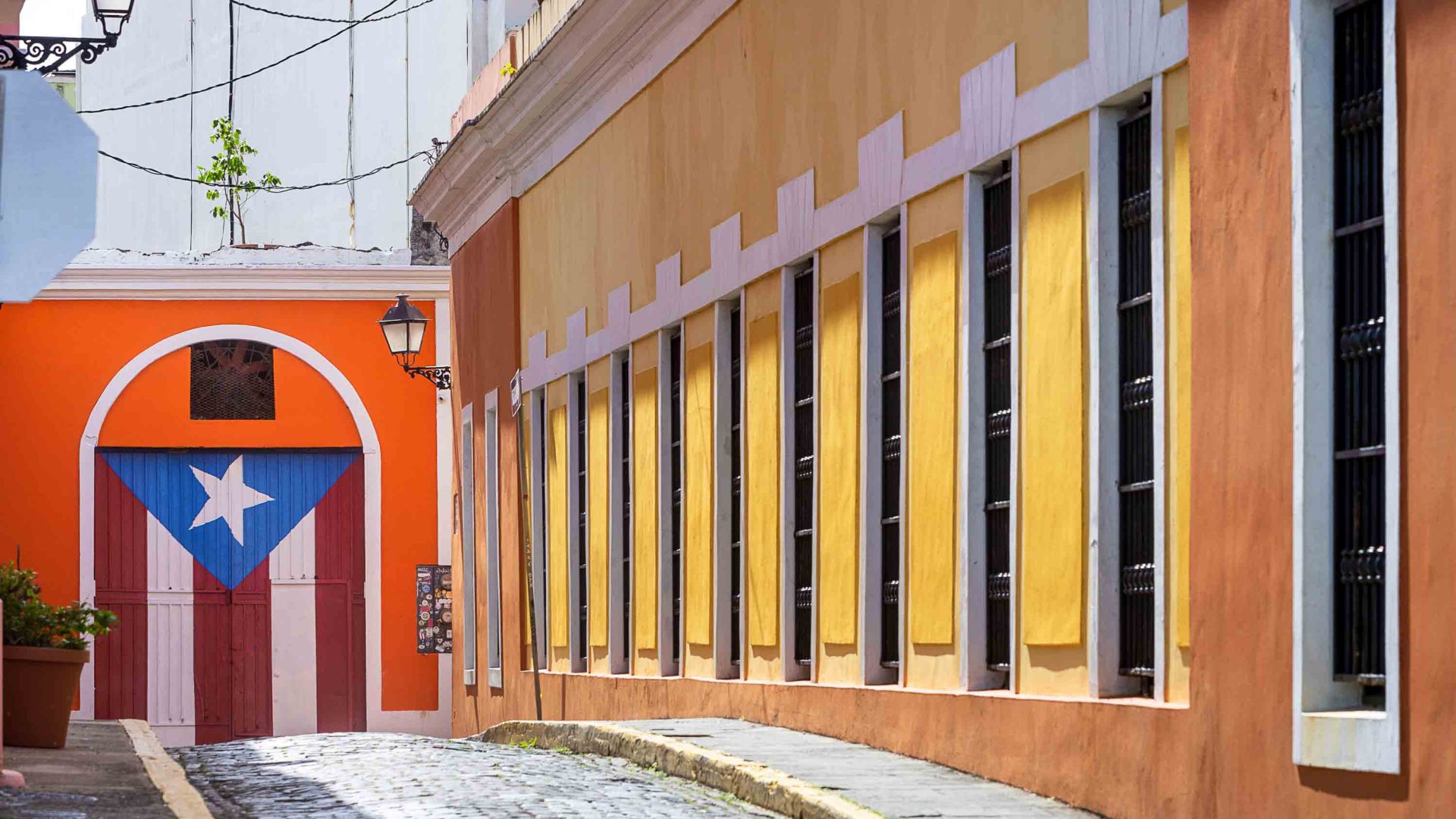 A yellow building leads to a wall painted with the Puerto Rican flag.