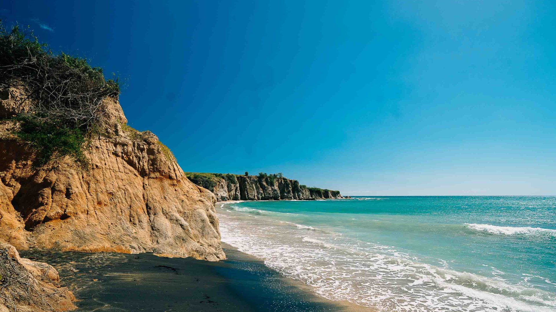 A beach with cliffs leading down to the water.