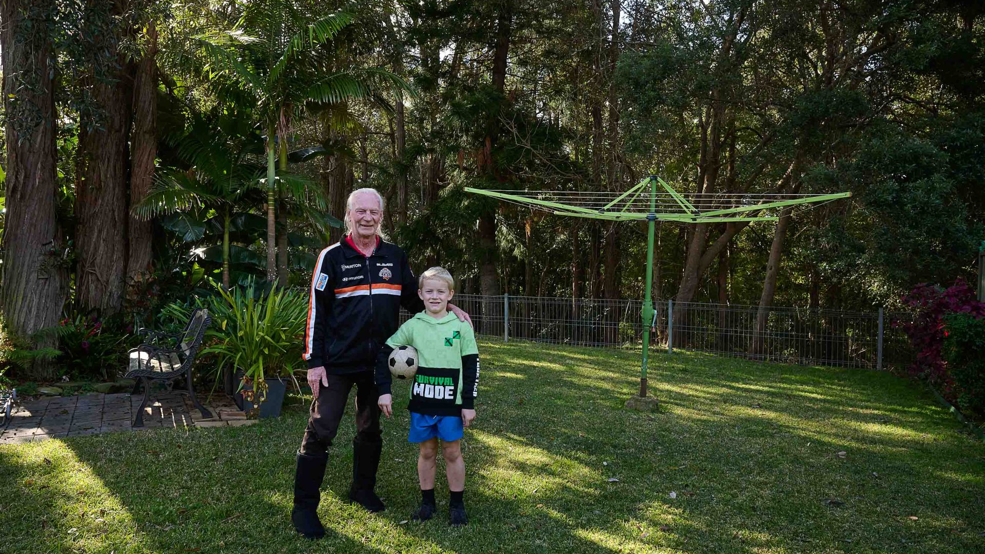 A man and his son stand in their backyard in front of their washing line.