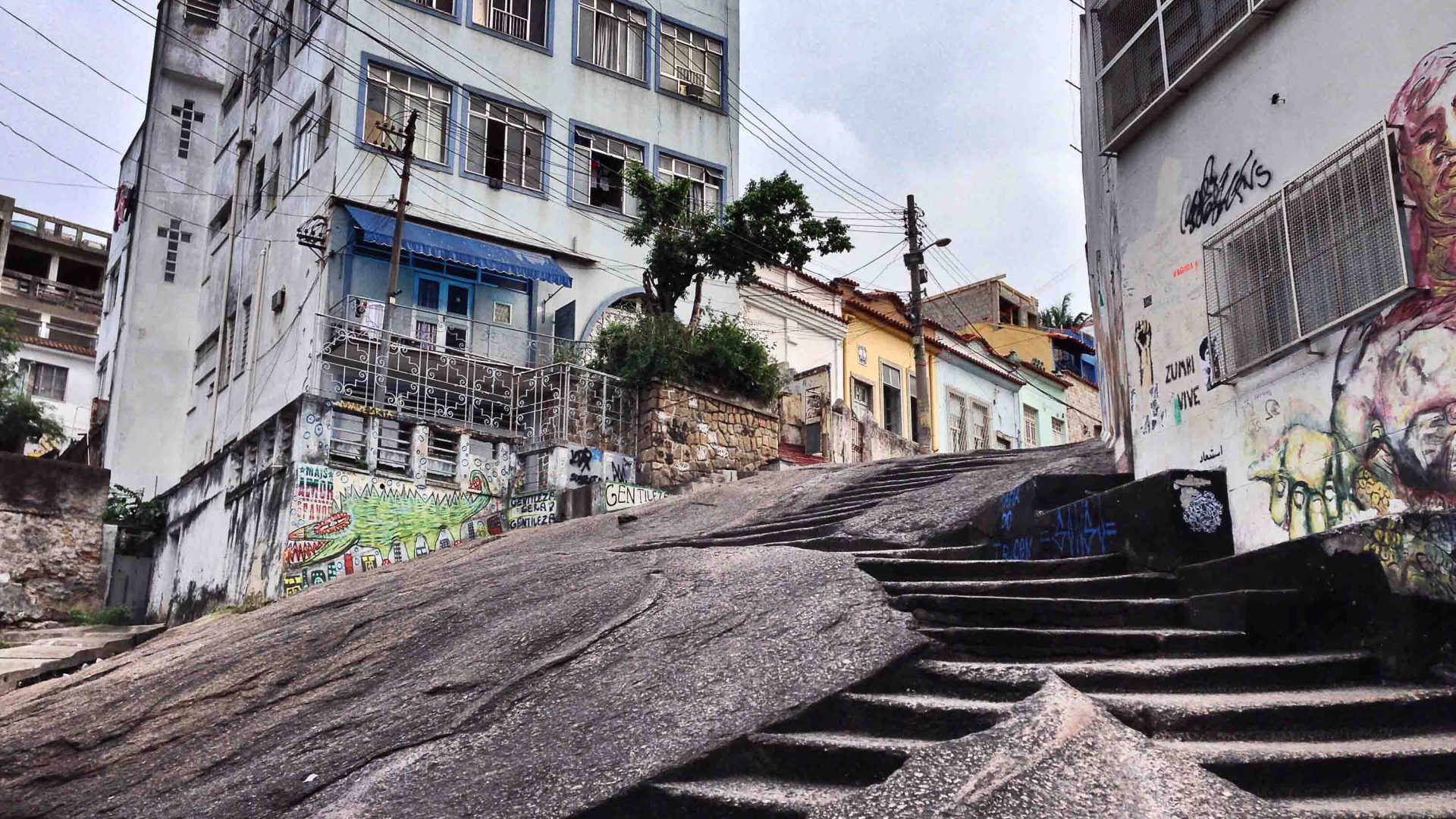 A staircase down a large rock, flanked by apartment buildings.