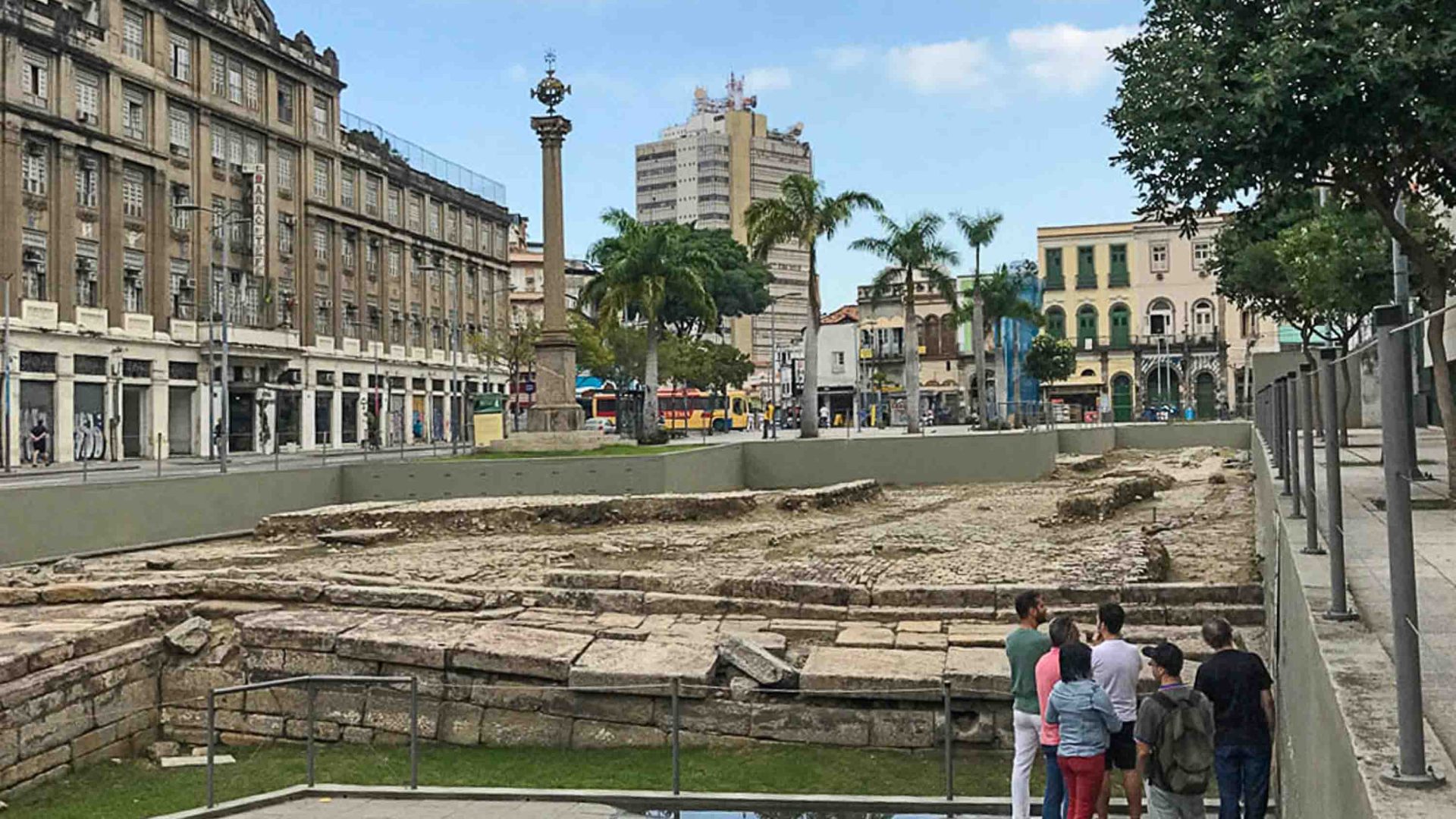 A group of people stand at the ruins of Valongo Wharf.