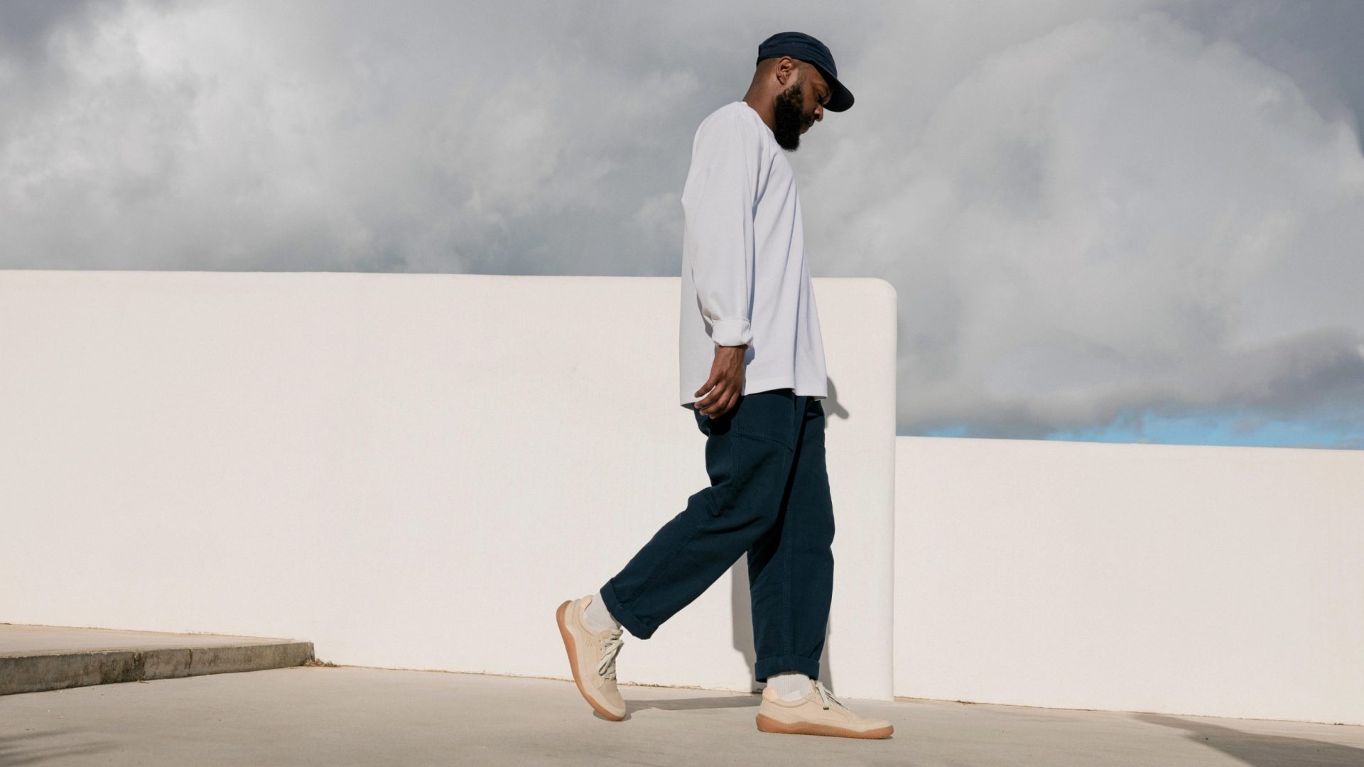 A man wearing white sneakers walks in a city.