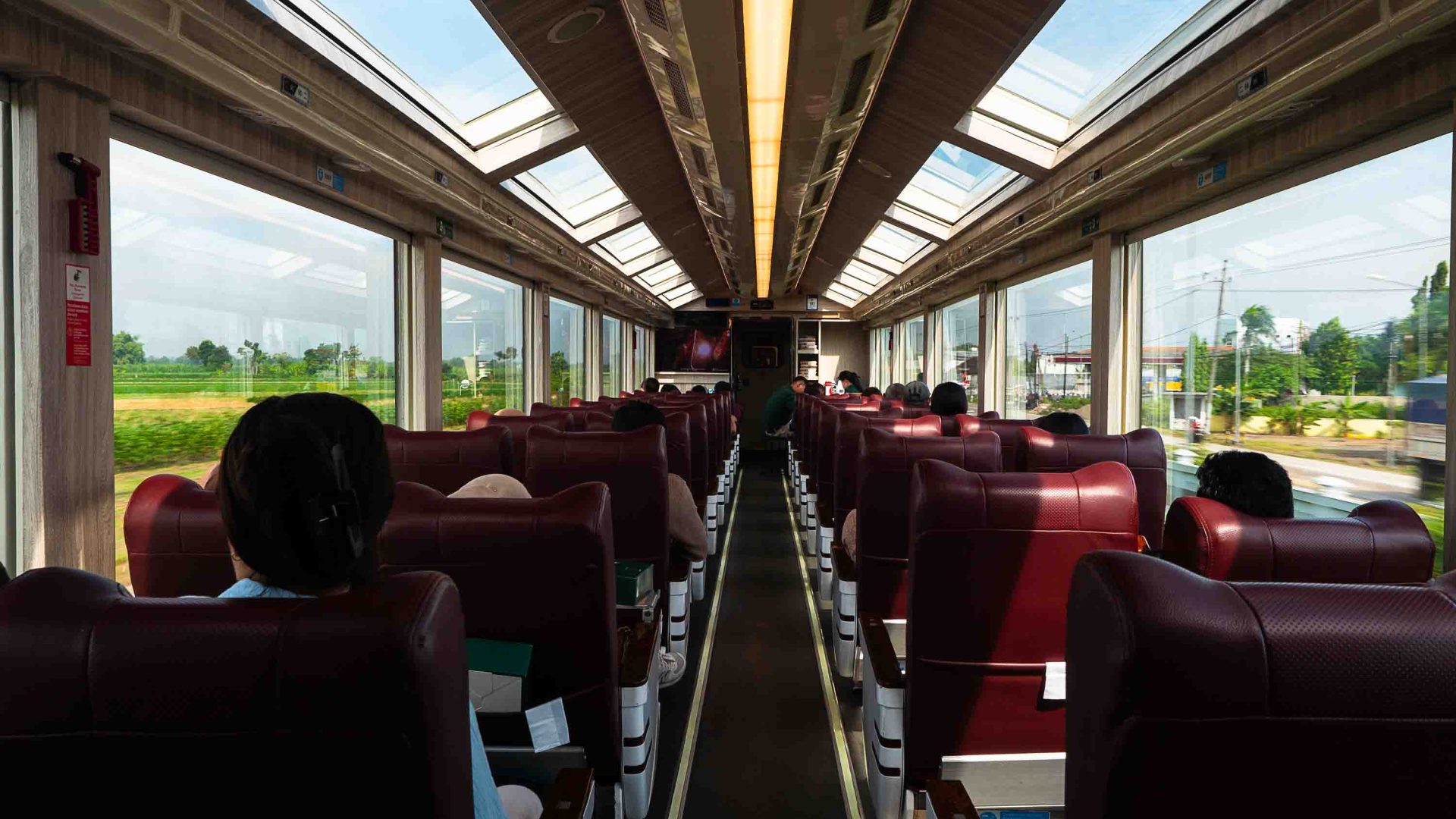 The red seats and ample windows of a train carriage interior.