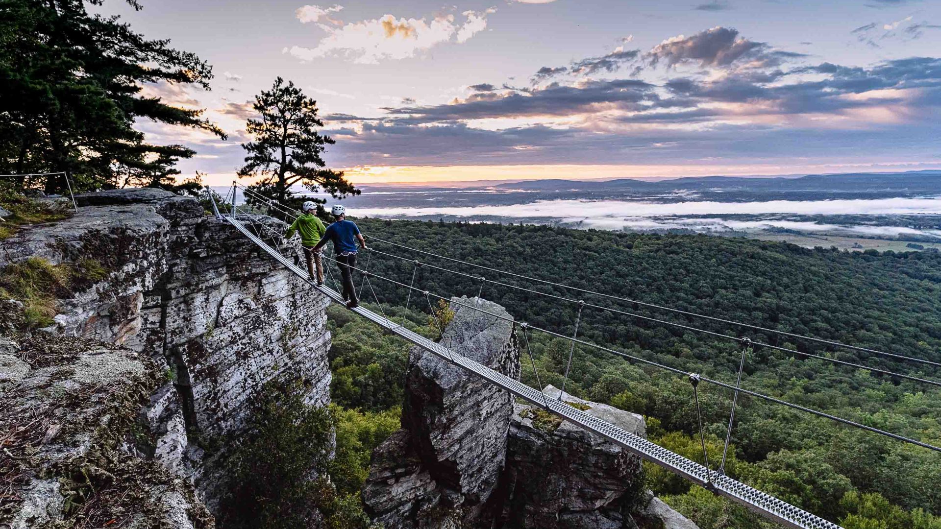 Two people look out at the vista at the end of the day from a via ferrata.