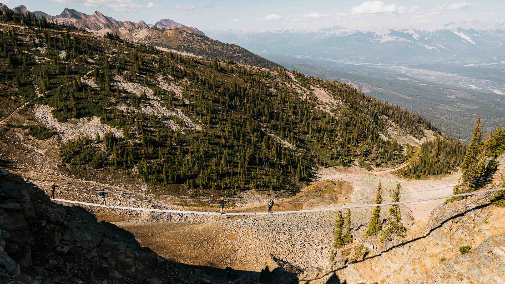 A via ferrata crosses a wide, arid valley.