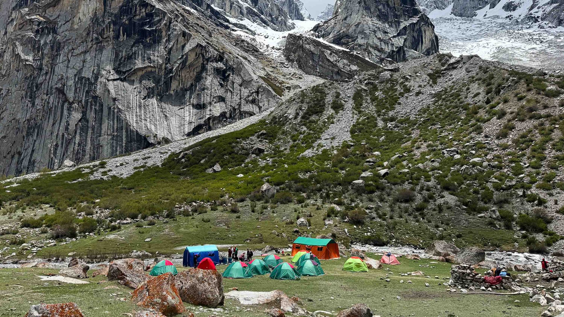 Colourful tents below tall mountains.