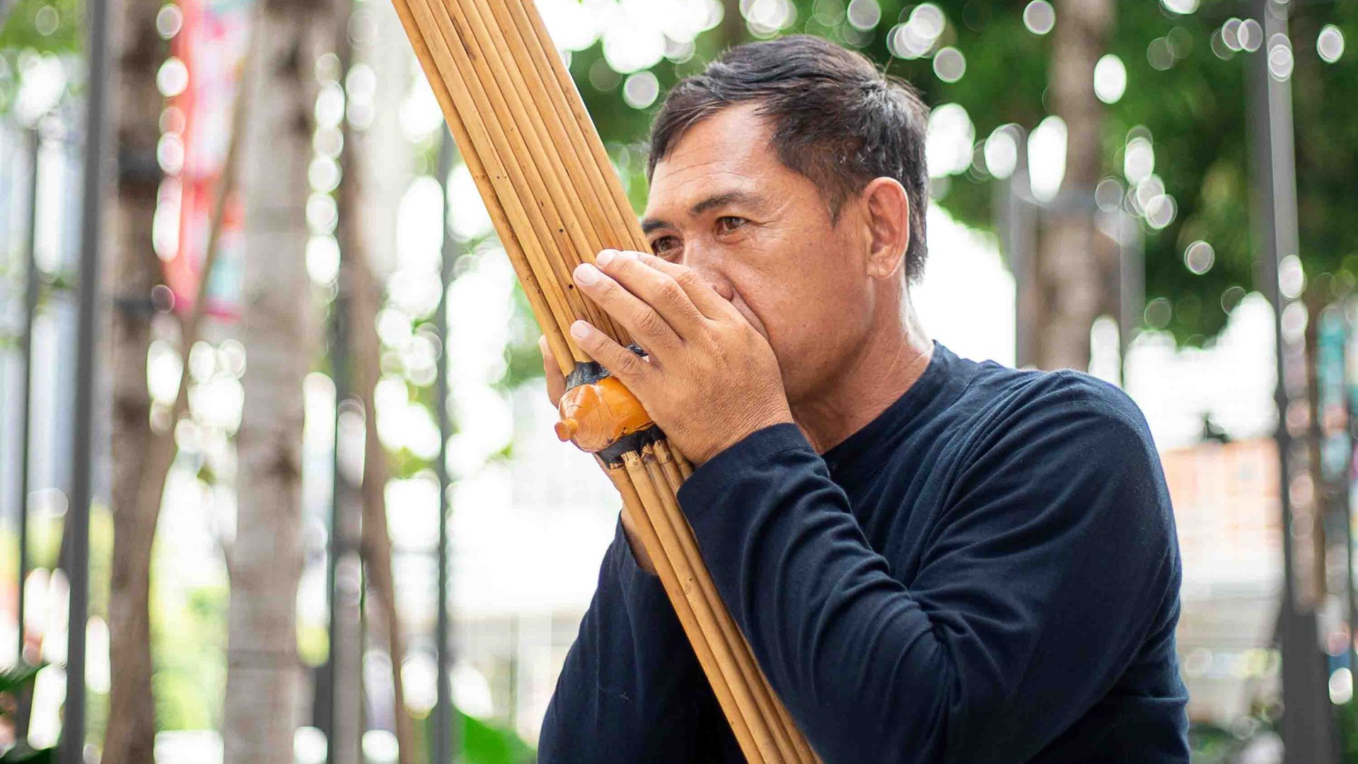 A man plays an instrument made of wood. He blows into it.