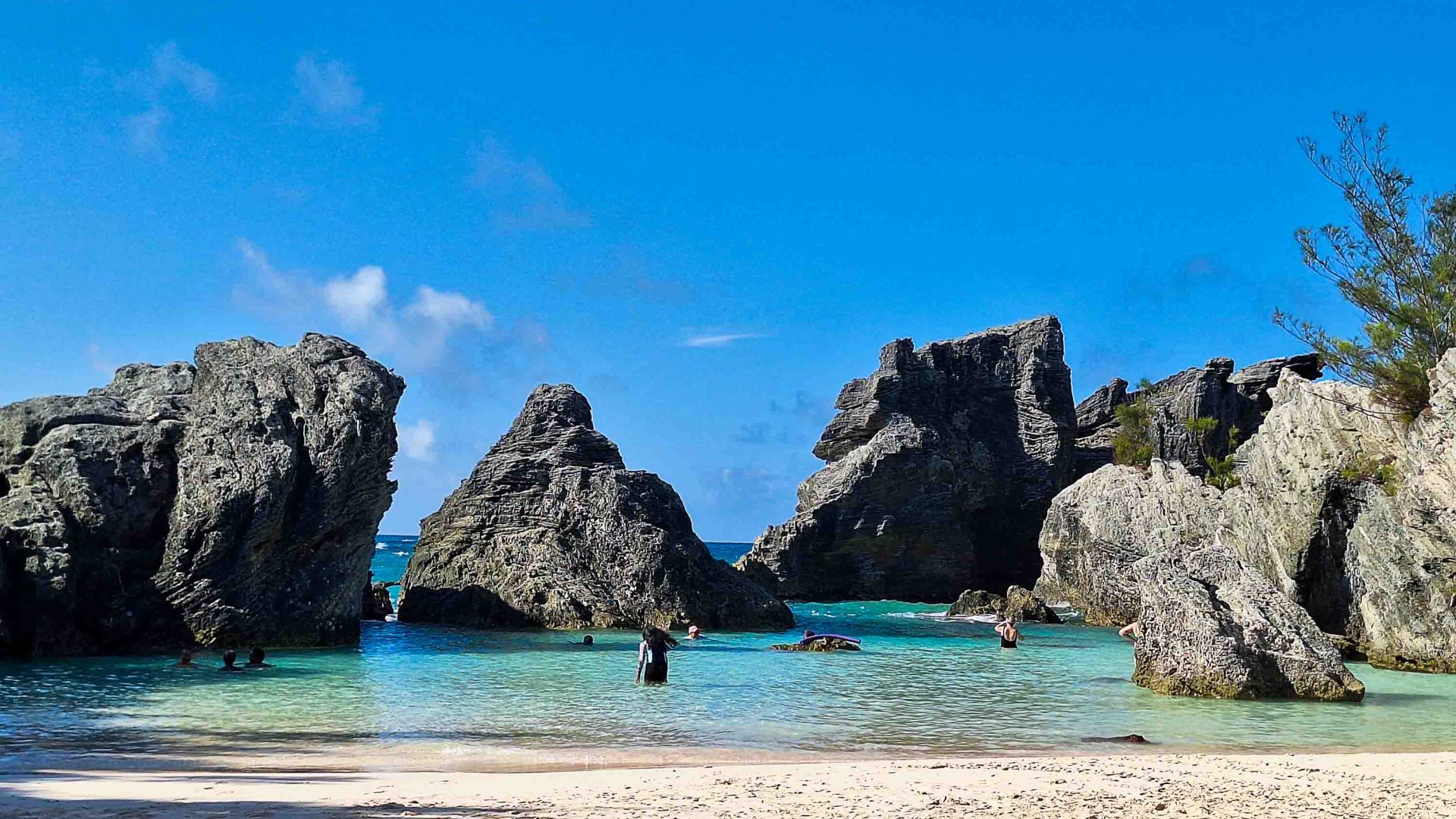 A beach with an area surrounded by rocks in the water.