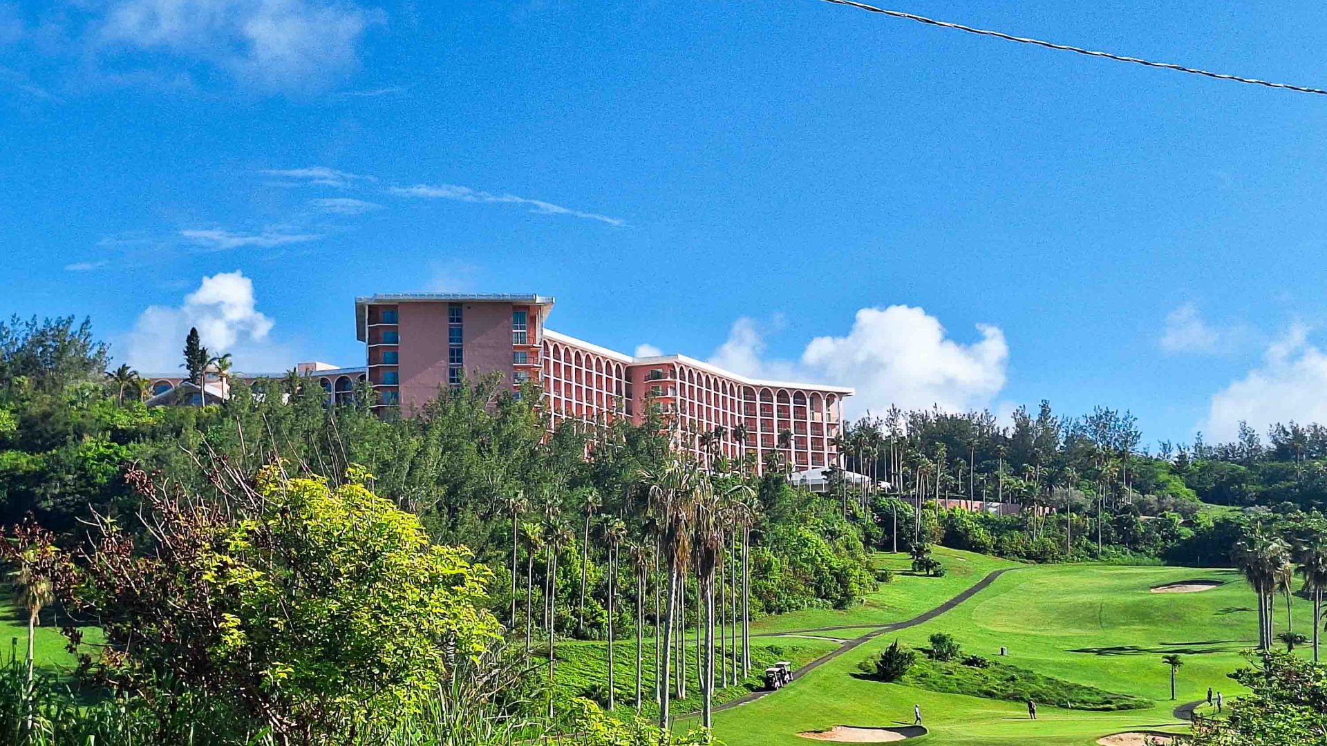 A large pink hotel towers above green golf courses.