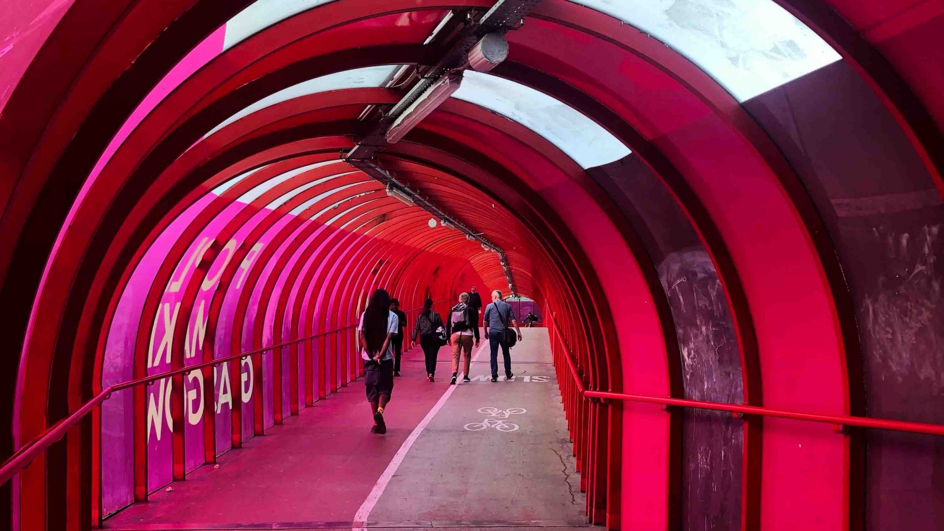 People walking through a pink tunnel.