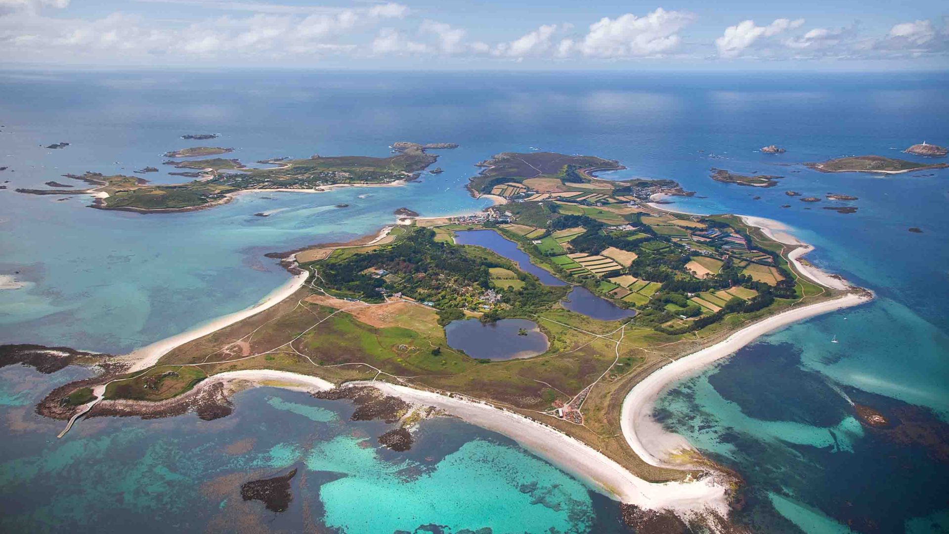 An aerial view of Tesco in the Scilly Isles. It is surrounded by blue water.