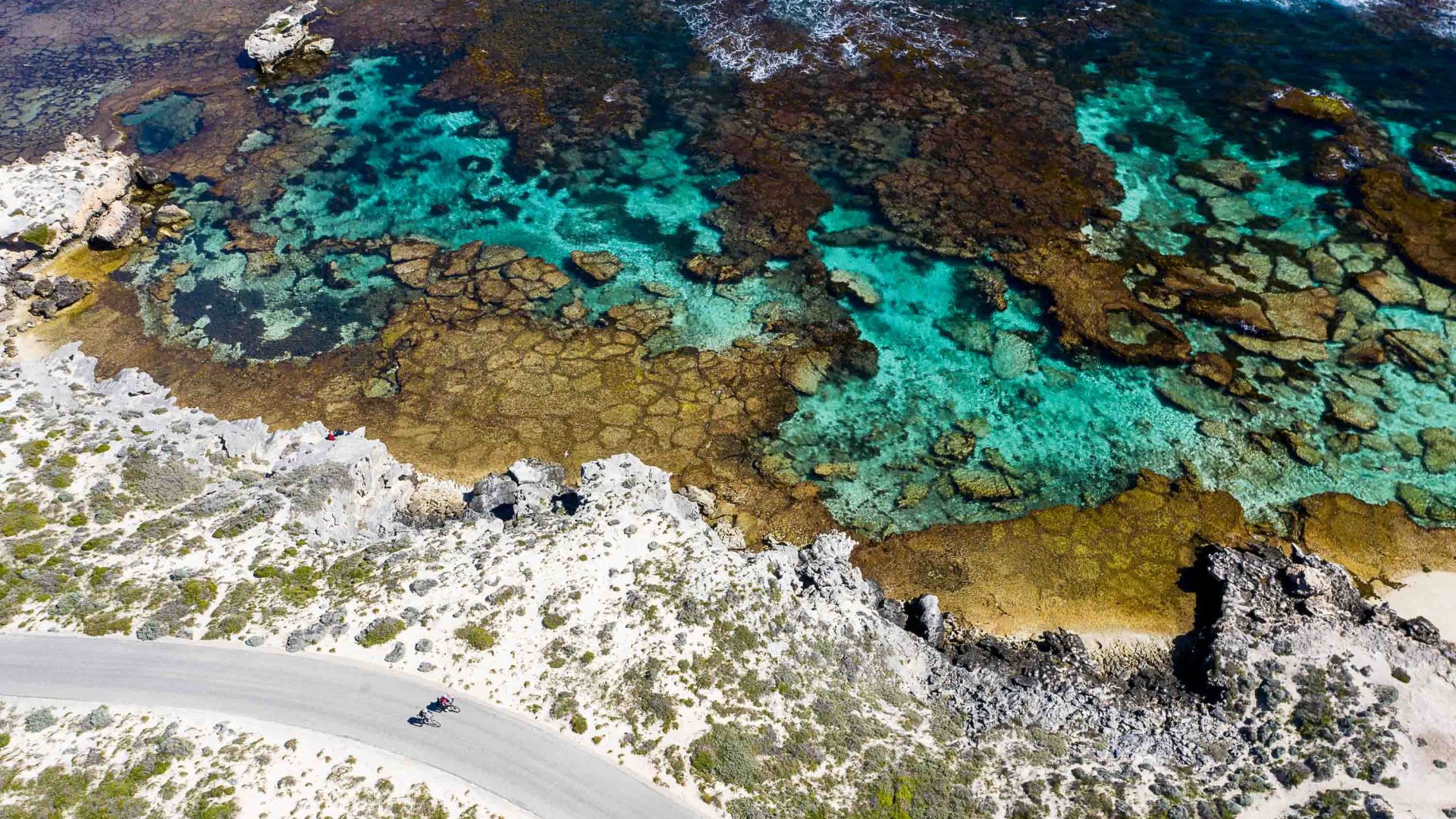 An aerial photo of a path winding past turquoise coast.